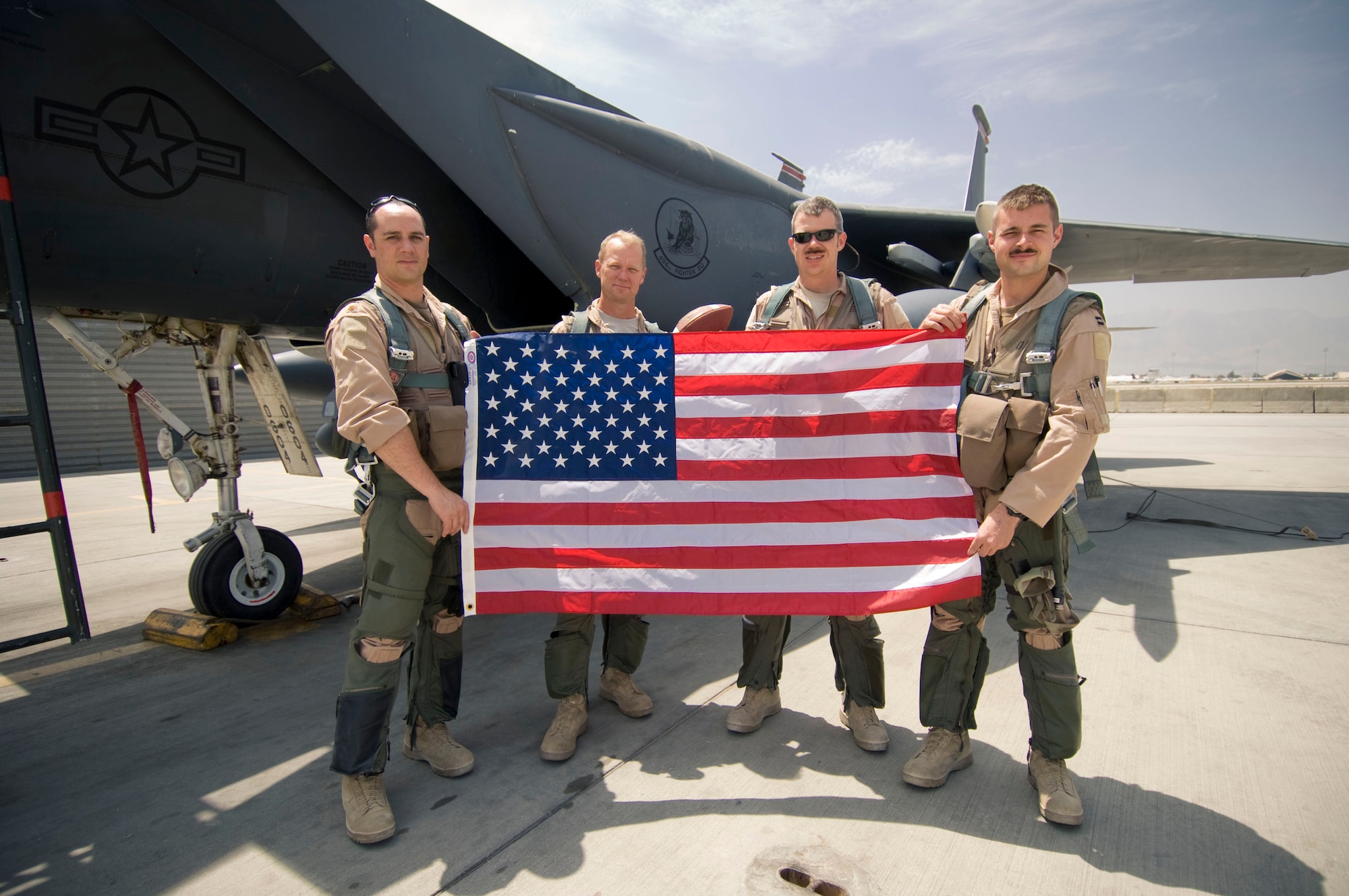 BAGRAM AIR FIELD, Afghanistan -- Maj. Richard Schreiber, Col. Mark Kelly, Maj. Roy Recker, and Capt. Christopher Koeltzow pose for a photograph with a flag and football in front of an F-15E Strike Eagle here on August 1, 2008. The flag and football accompanied the four on a combat mission over Afghanistan that day and were given to a child back in the United States who's illness prevented them from playing football anymore. (U.S. Air Force photo by Staff Sgt. Samuel Morse)