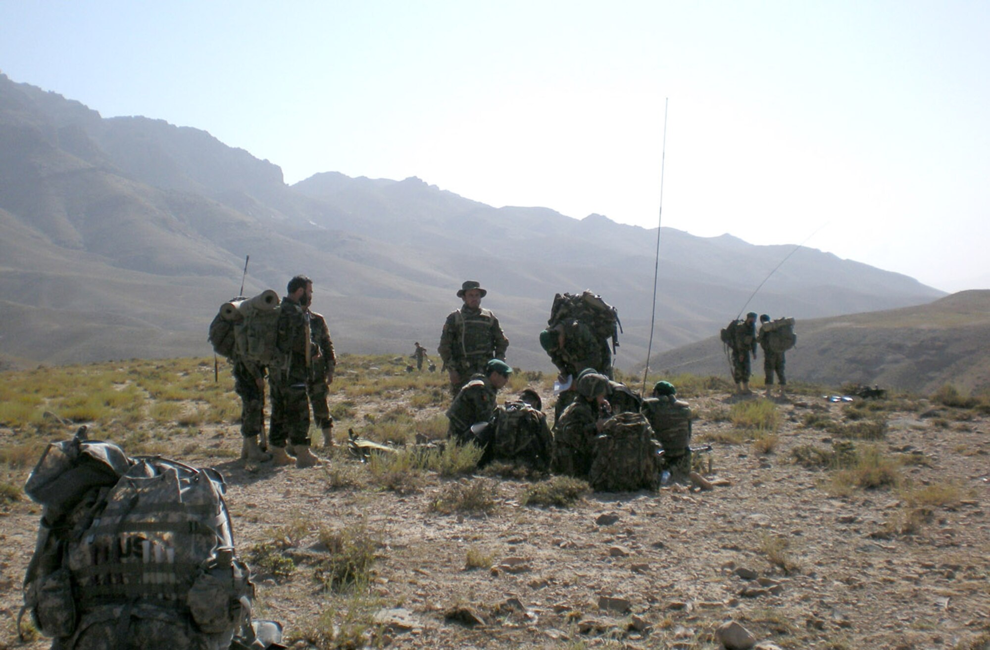 Afghan National Army troops, with their Coalition forces counterparts, take a short halt during a mission in the Jowzak area of Afghanistan, July 22. They were part of an air reconnaissance mission that was taking place for this area in effort to reach out to the local villagers and sweep the area of anti-Afghan forces. (Courtesy photo)
