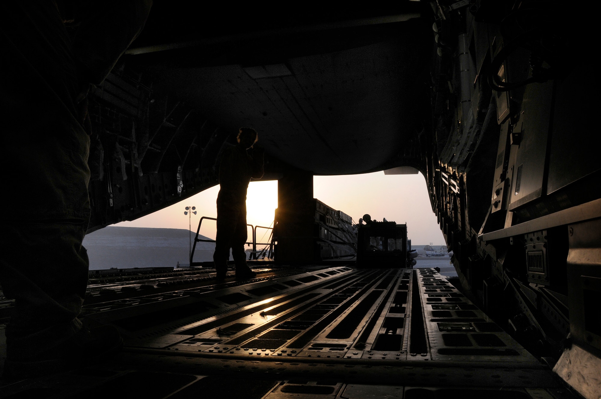 The setting sun silhouettes pallets of cargo being loaded onto a C-17 Globemaster III at an undisclosed air base in Southwest Asia Aug. 8, 2008.  Pallets of supplies and equipment are loaded onto the aircraft for delivery to locations up range in support of Operations Iraqi Freedom and Enduring Freedom. (U.S. Air Force photo by Tech. Sgt. Michael Boquette/Released)