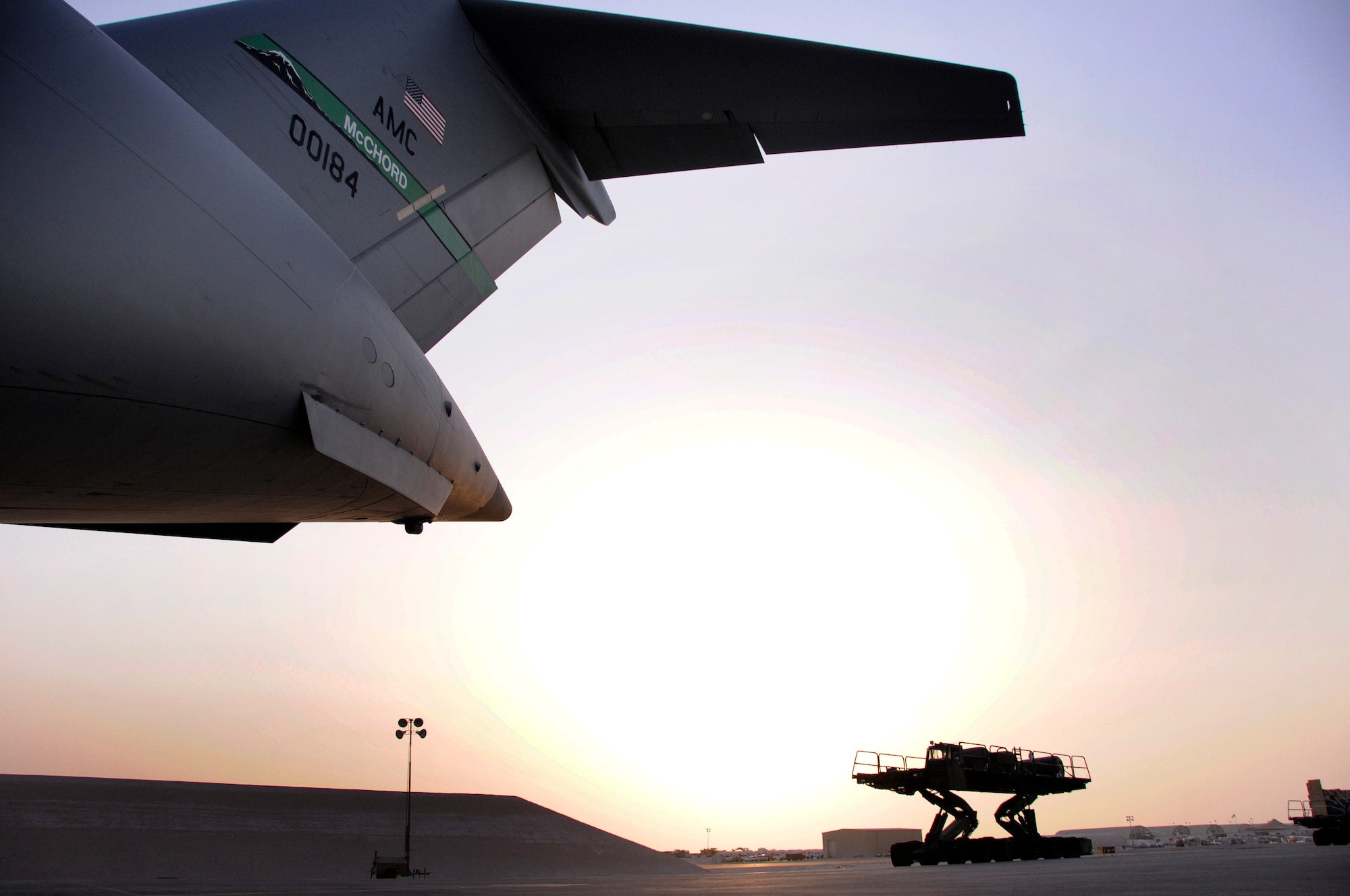 A 60K Loader is dwarfed by a C-17 from McChord Air Force Base, Wash., as the loader moves through the sunset to deliver cargo Aug. 8, 2008.  Two 60K Loaders filled with pallets are loaded onto the C-17 to deliver equipment and supplies to bases up range in support of Operations Iraqi Freedom and Enduring Freedom from an undisclosed air base in Southwest Asia.  (U.S. Air Force photo by Tech. Sgt. Michael Boquette/Released)