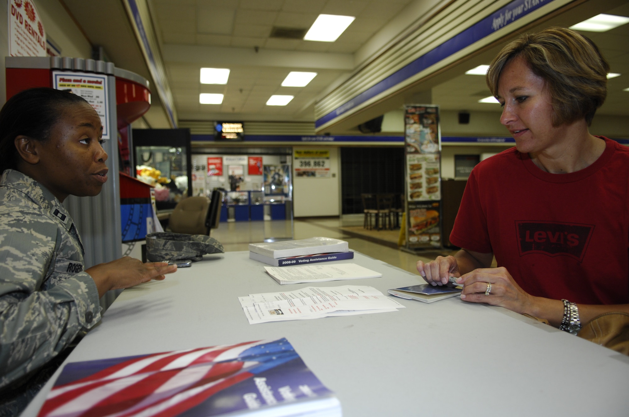 MINOT AIR FORCE BASE, N.D. – Capt. Allison Rogers, 5th Medical Group executive officer, gives voting information to Marci Rockhold, wife of Senior Master Sgt. Todd Rockhold, 5th Munitions Squadron first sergeant, at the voter registration booth in the Base Exchange here Aug. 7. Captain Rogers volunteered her time to act as the 5th MDG voting representative, as well as work at the registration booth supporting the base-wide voter registration drive held Aug. 4 to 8. (U.S. Air Force photo by Staff Sgt. Thomas Dow)