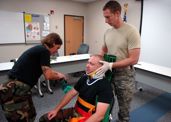 MOODY AIR FORCE BASE, Ga. – Staff Sgt. Christopher Spencer, 23rd Medical Group emergency medical technician holds the head of Master Sgt. Robert Karbach, 820th Security Forces Group independent duty medical technician, in place, while Staff Sgt. Erin Grimme, 75th Fighter Squadron independent duty medical technician, fastens straps around him here Aug. 6. Sergeant Grimme and Sergeant Spencer simulate steps taken to secure a car accident victim during a patient medical assessment. (U.S. Air Force photo by Airman Joshua Green) 