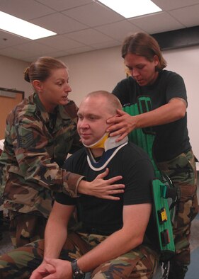 MOODY AIR FORCE BASE, Ga. – Tech. Sgt. Charity Gerner, 23rd Aerospace Medical Squadron NCO in-charge of ambulance dispatch, and Staff Sgt. Erin Grimme, 75th Fighter Squadron independent duty medical technician, lean forward Master Sgt. Robert Karbach, 820th Security Forces Group independent duty medical technician, to slide a Kendrick extraction device behind his back here Aug. 6. The KED is used to keep accident victim’s head and back stabilized to minimize further injury. (U.S. Air Force photo by Airman Joshua Green)   