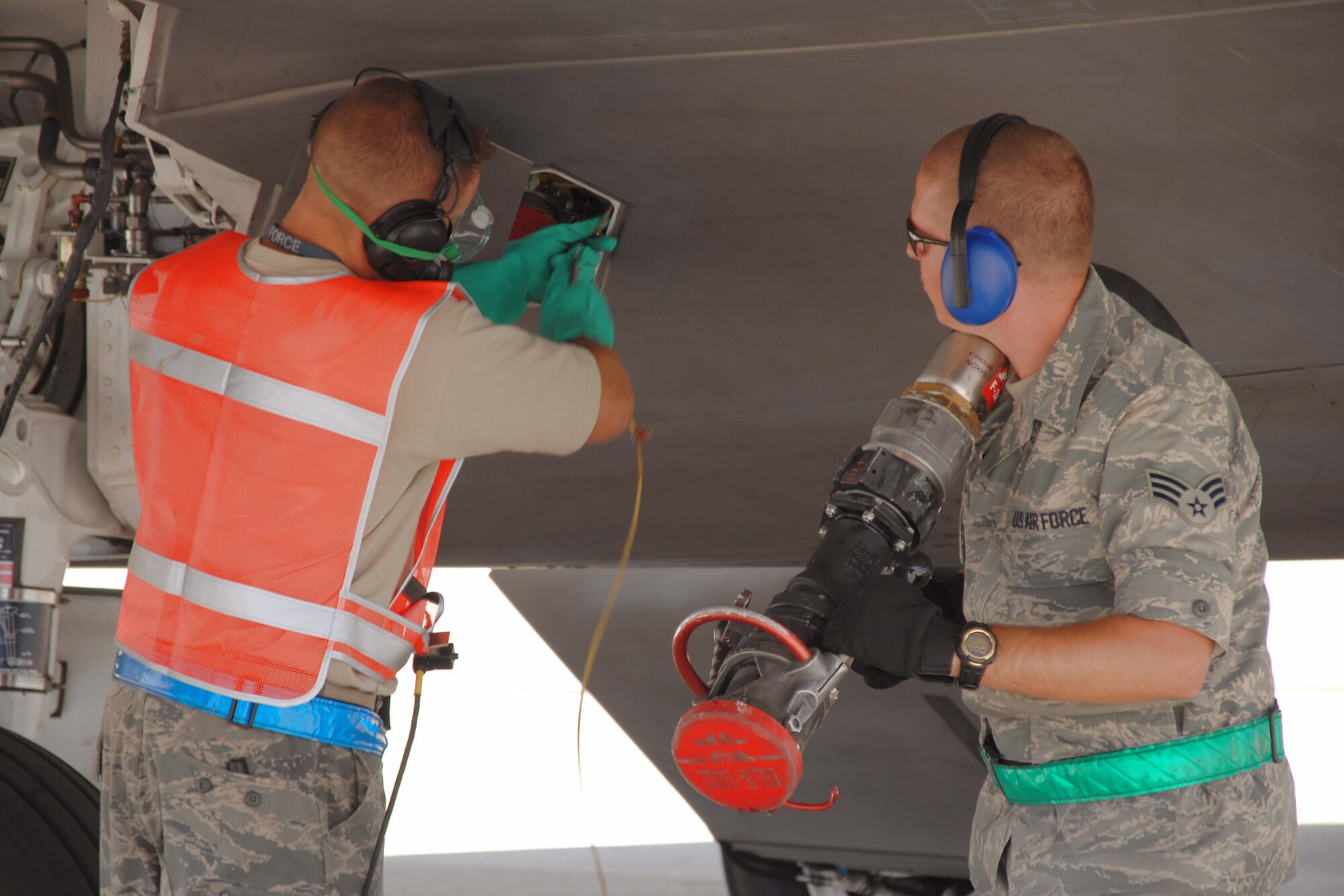 Senior Airman Kurtis Toycen, a fuels specialist with the 49th Logistics Readiness Squadron at Holloman Air Force Base, N.M., secures a refueling hose July 23, while Tech. Sgt. Aaron Cowan, a maintainer with the 49th Aircraft Maintenance Squadron, locks the fuel receptacle on an F-22 Raptor.  The team successfully refueled the aircraft while its engines were still running, a procedure called "hot refueling."  (U.S. Air Force photo/Airman 1st Class Jamal D. Sutter)