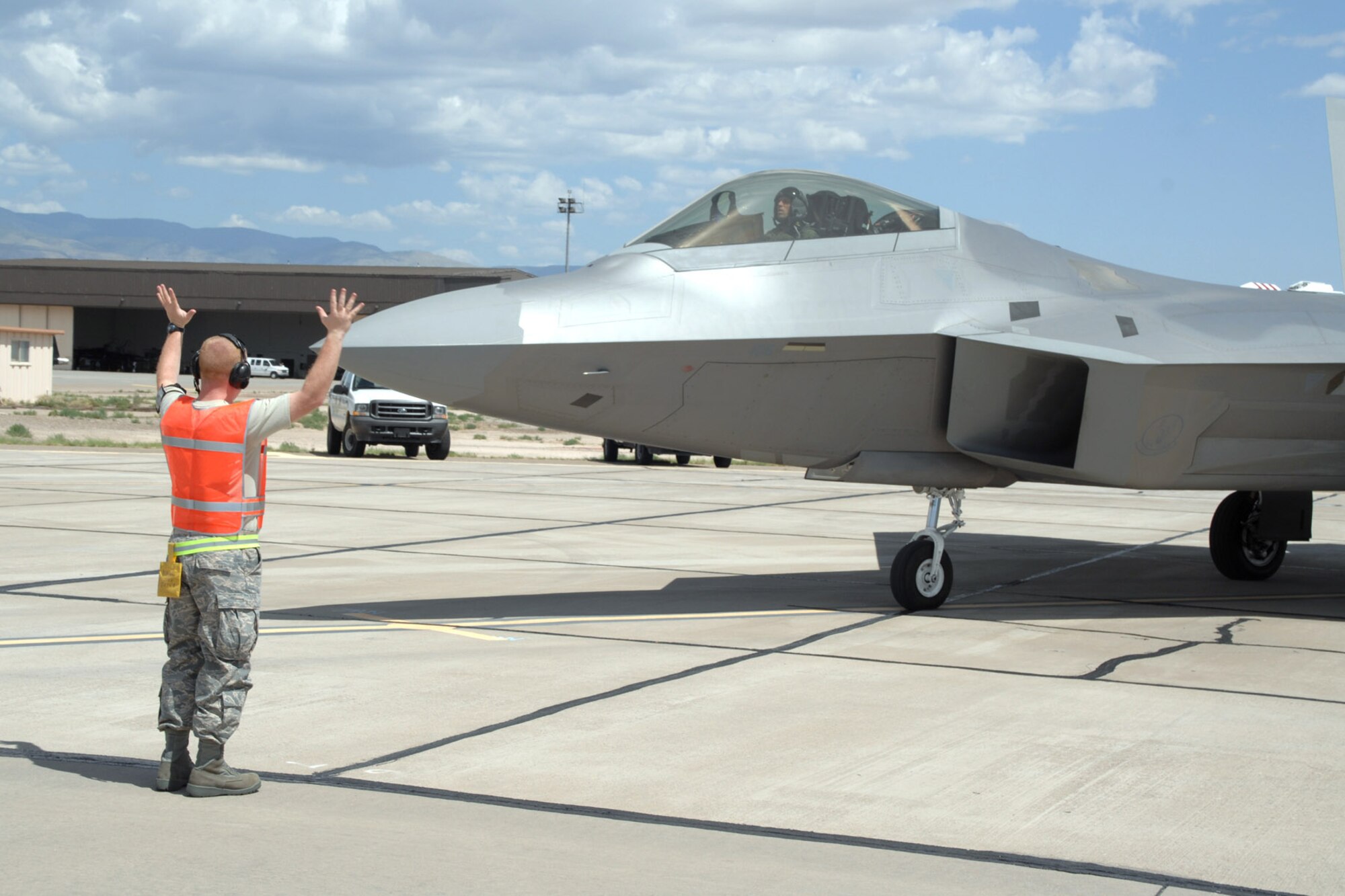 Tech. Sgt. Dennis Thomas, a maintainer with the 49th Aircraft Maintenance Squadron at Holloman Air Force Base, N.M., marshals an F-22 Raptor July 23 in preparation for a hot refueling. Hot refueling is a procedure used to refuel an aircraft while the engines are still running, cutting the time needed to refuel in more than half. (U.S. Air Force photo/Airman 1st Class Jamal D. Sutter)