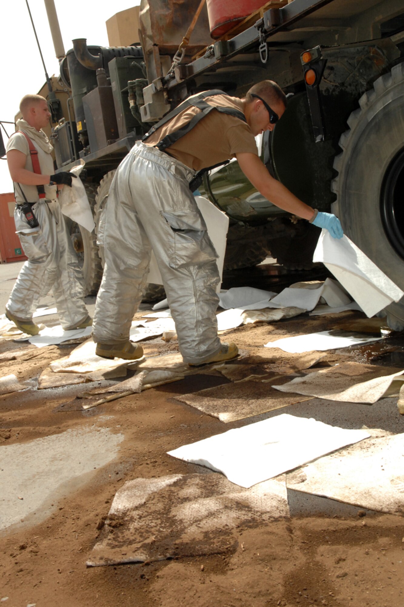 KIRKUK REGIONAL AIR BASE, Iraq -- Airmen 1st Class Clovis Jewell (foreground) and Zackery Williams, 506th Expeditionary Civil Engineer Squadron firefighters, clean up a fuel spill here Aug 7.  The Airmen were two of 10 firefighters responding to the spill which was cleaned up with no environmental impact.  Airman Jewell is deployed from Ramstien Air Base, Germany, and calls Texarcana, Ark.  Airman Williams is deployed from Grand Forks, N.D., and calls Fort Mitchell Ky., home.  (U.S. Air Force photo/Senior Airman Randi Flaugh)