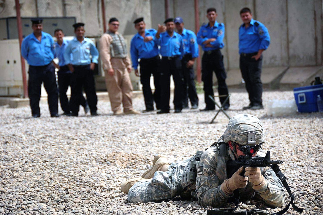 U.S. Army Sgt. Steven Ippel demonstrates tactical maneuvering to Iraqi policemen as part of an informal combat skills training course U.S. soldiers are providing to Iraqi police at the Hammiyat police station in Taji, Iraq, Aug. 4, 2008. 