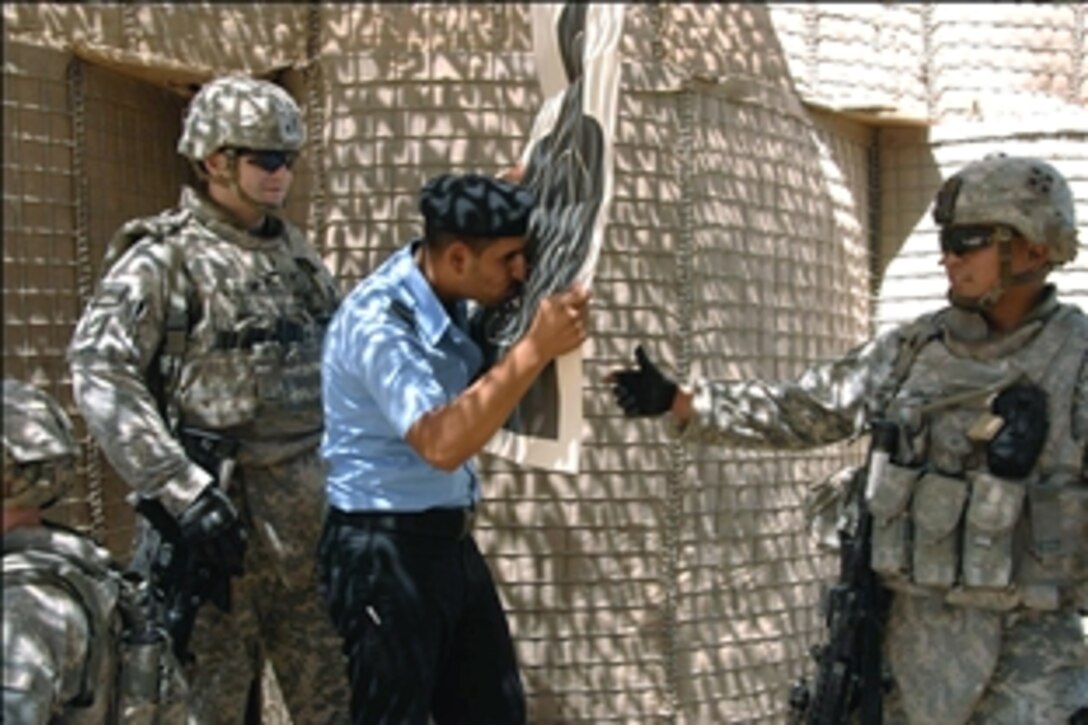 U.S. Army 1st Lt. Kevin Smith, left, and a fellow soldier watch as an Iraqi police officer kisses his target during Basic Rifle Marksmanship training at Forward Operating Base Prosperity, Baghdad, Iraq, Aug. 6, 2008. Smith and fellow soldiers are assigned to the 4th Infantry Division's Battery A, 4th Battalion, 42nd Field Artillery, 1st Brigade Combat Team.