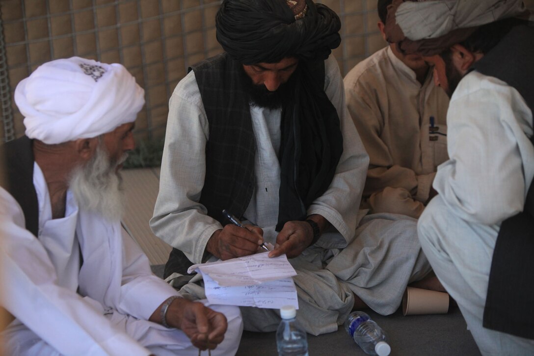 A local village elder signs his name alongside other village elders to agree on all the issues discussed during the weekly shura with Lima Co., 3rd Battalion, 1st Marine Regiment, in Garmsir District, Afghanistan, June 17, 2010. The local shura is to help build the relationship with the elders, Afghan National Army and the Marines.