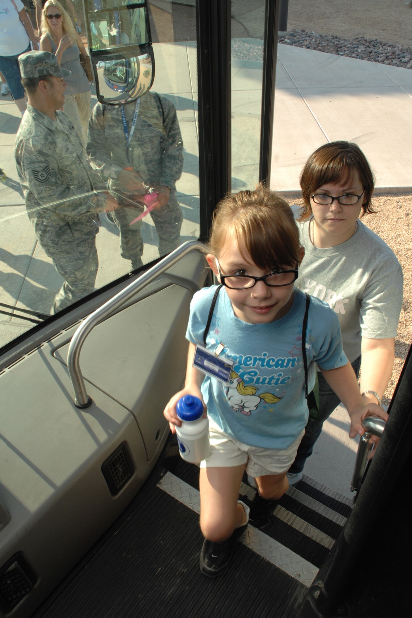 Lauren, 8, and her mother, Tiffani Trojca, 49th Fighter Wing Public Affairs, enters a bus that will take them to a mock deployed location Aug. 7 at Holloman Air Force Base, N.M. Once at the deployed location, Balad Air Base, Iraq, the children received a safety and intelligence brief and were able to take part in the hands-on educational stations that were set up throughout the area. (U.S. Air Force photo/Airman 1st Class Jamal D. Sutter)