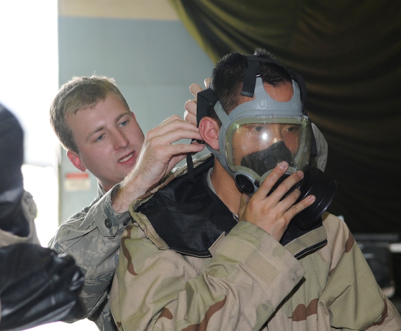 Airman 1st Class Shawn Barnett, 305th Civil Engineer Squadron, helps a student with his gas mask during the Ability to Survive and Operate training class Aug. 5 here. The 305th CES Readiness and Emergency Management Flight hosts the ATSO training, which is required for McGuire personnel who will be participating in mobility exercises and/or the upcoming Operational Readiness Inspection. (U.S. Air Force photo/Kenn Mann)