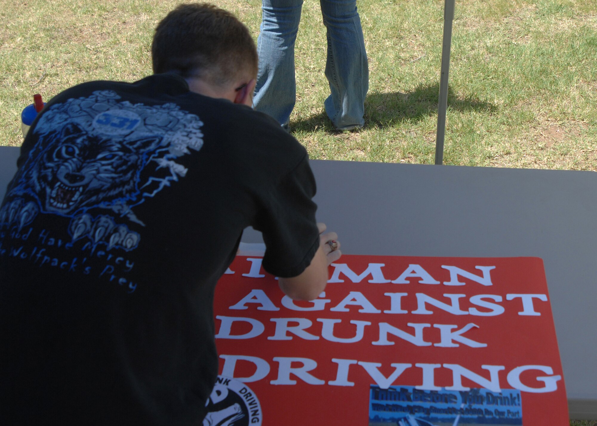 CANNON AIR FORCE BASE, N.M. --Senior Airman Carl Williams, 27th Special Operations Communications Squadron, readies an Airman Against Drunk Driving poster for display during Cannon Appreciation Days Aug. 8. The Cannon community of Airmen, their families and base employees enjoyed an afternoon of food, drink, games and prizes, courtesy of Clovis, N.M. community leaders and businesses during  the 19th annual event. (U.S. Air Force photo by Greg Allen)