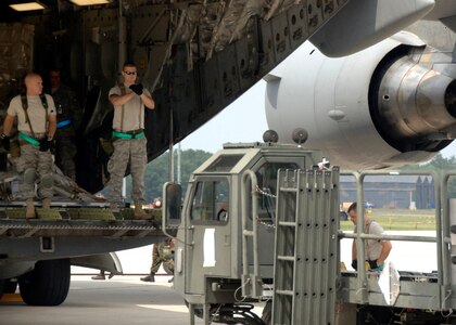 Airmen from the 437th Aerial Port Squadron guide a 60k loader to the back of a C-17 Aug. 7 to unload supplies for the operational readiness inspection at a simulated air base in East Asia. Timely loading and unloading of planes on the flightline is one of the first steps to success for any operation. (U.S. Air Force photo/Airman 1st Class Timothy Taylor)