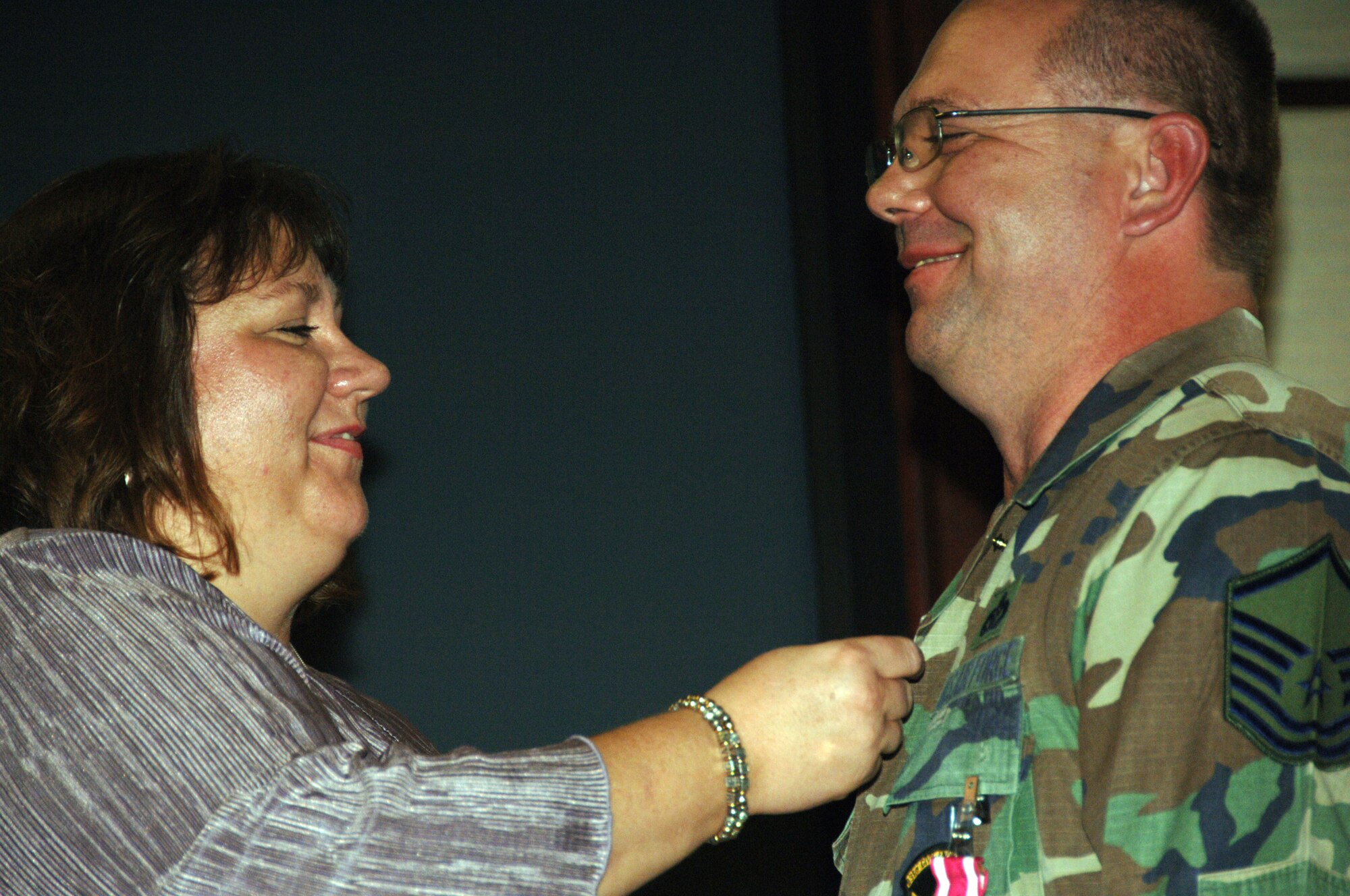 Rebecca Gobel places a retirement pin on her husband, Master Sgt. Shelby Gobel, during his retirement ceremony on Aug. 9.  Sergeant Gobel retired from the 931st Civil Engineer Squadron two years after he collided with a deer while riding a motorcycle.