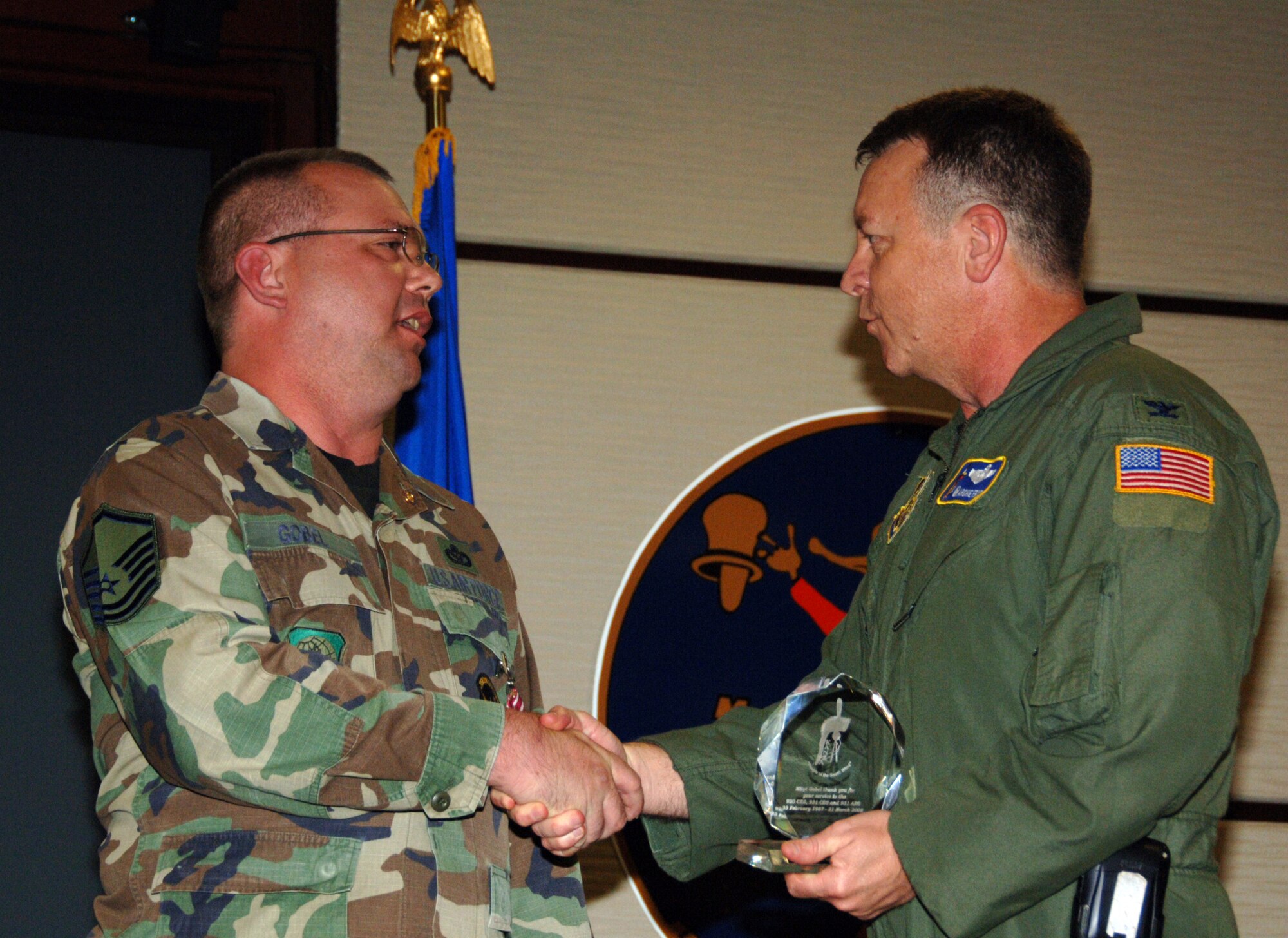 Master Sgt. Shelby Gobel accepts a commander's coin and Kanza Roach Crystal from Col. Edsel "Archie" Frye Jr., 931st Air Refueling Group Commander, during a retirement ceremony on Aug. 9.  Sergeant Gobel retired from the 931st Civil Engineer Squadron two years after he collided with a deer while riding a motorcycle.  The crystal is given to charter members of the 931st ARG.