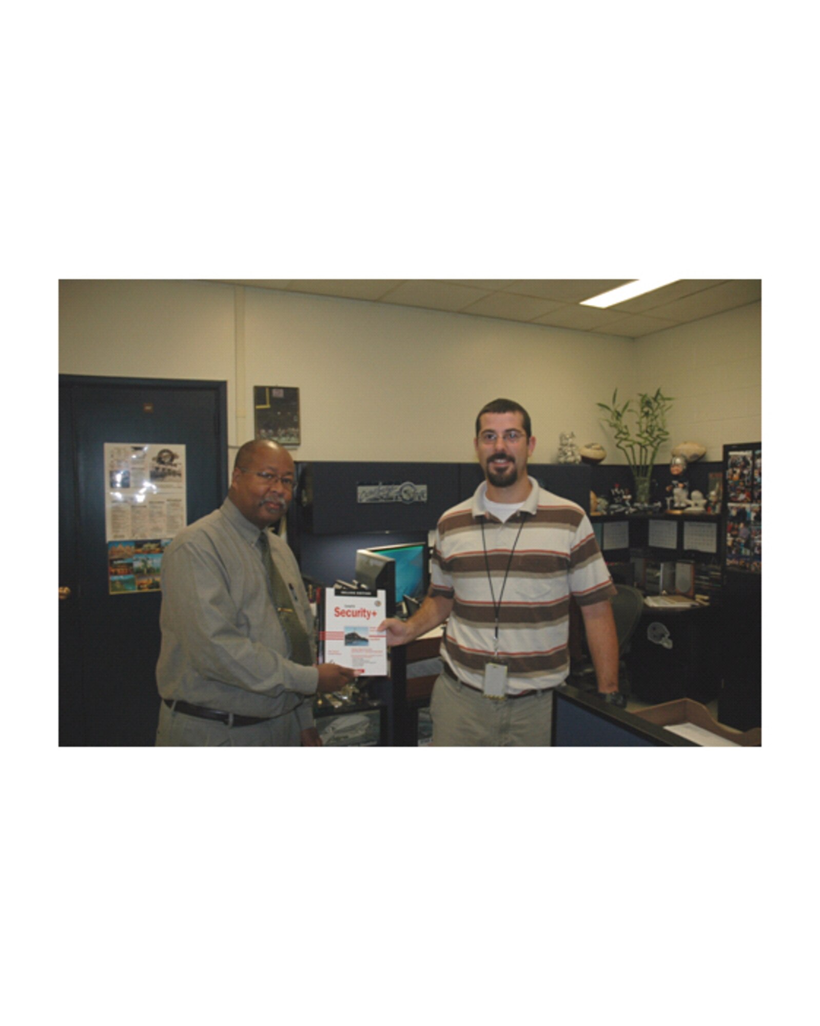 Mr. Ken Perkins (left), deputy, Chief Information Office,  issues a SECURITY + book to Mr Jeff Mixson, who has the additional duty of client systems administrator for the 96th Communication Group.