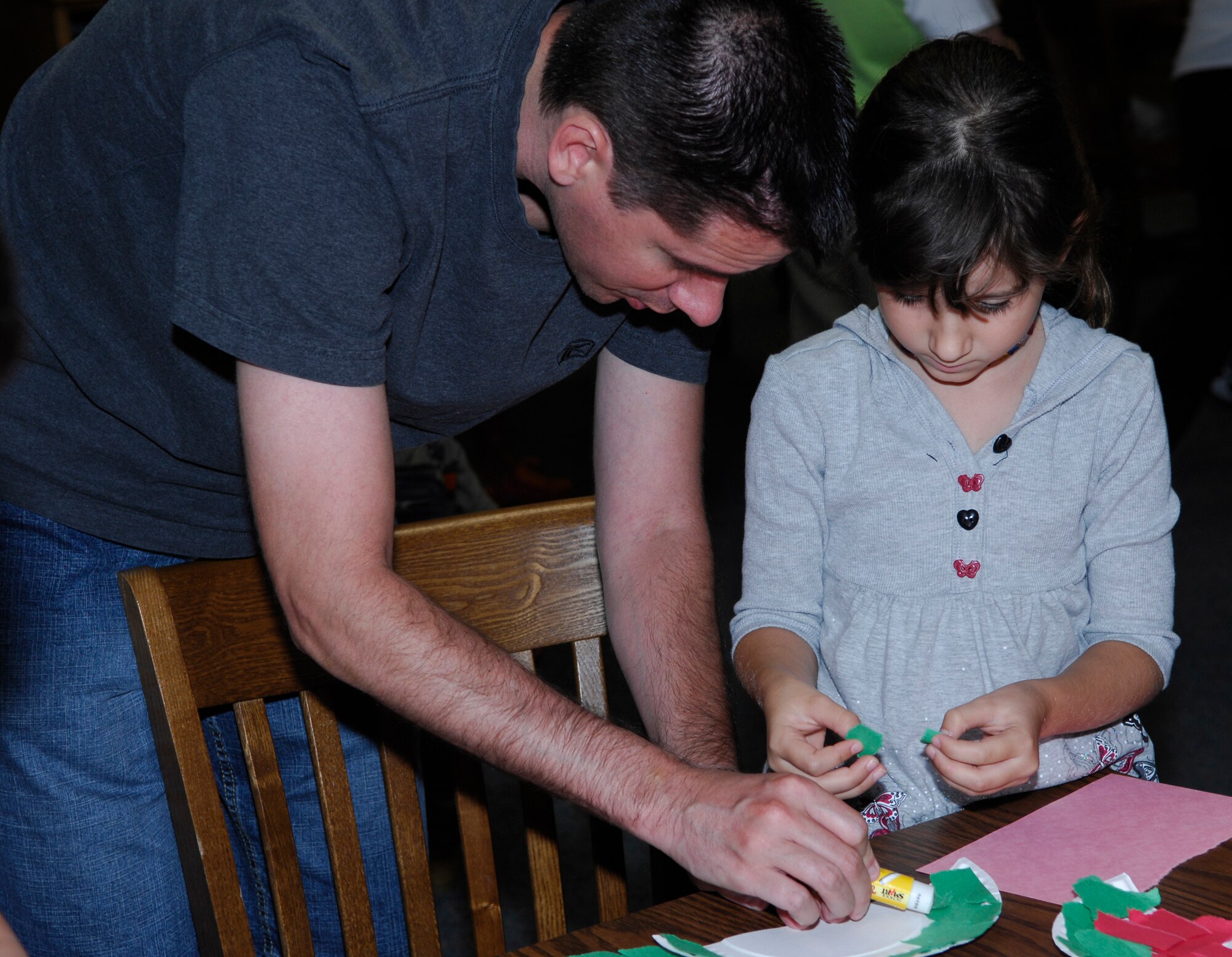 MINOT AIR FORCE BASE, N.D. – Master Sgt. Todd Johnson, 5th Comptroller Squadron financial management flight chief, helps his daughter, Morgan, with a watermelon craft project during the Summer Reading Program wrap-up celebration held at the base library here Aug. 9. This year the base library had a total of 304 children and adults enjoy the summer-long reading program’s activities. (U.S. Air Force photo by Tech. Sgt. Marelise Wood)
