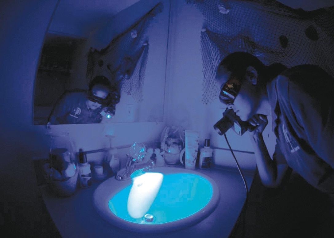 Special Agent Martha Ward, Forensic Science Consultant, 2nd Field Investigations Squadron, AFOSI Region 7, uses the Forensic Light Source to look for evidence composed of biological material such as teeth, bone fragments, and blood, during a training scenario July 17. (U.S. Air Force photo/Senior Airman Renae Kleckner) 
