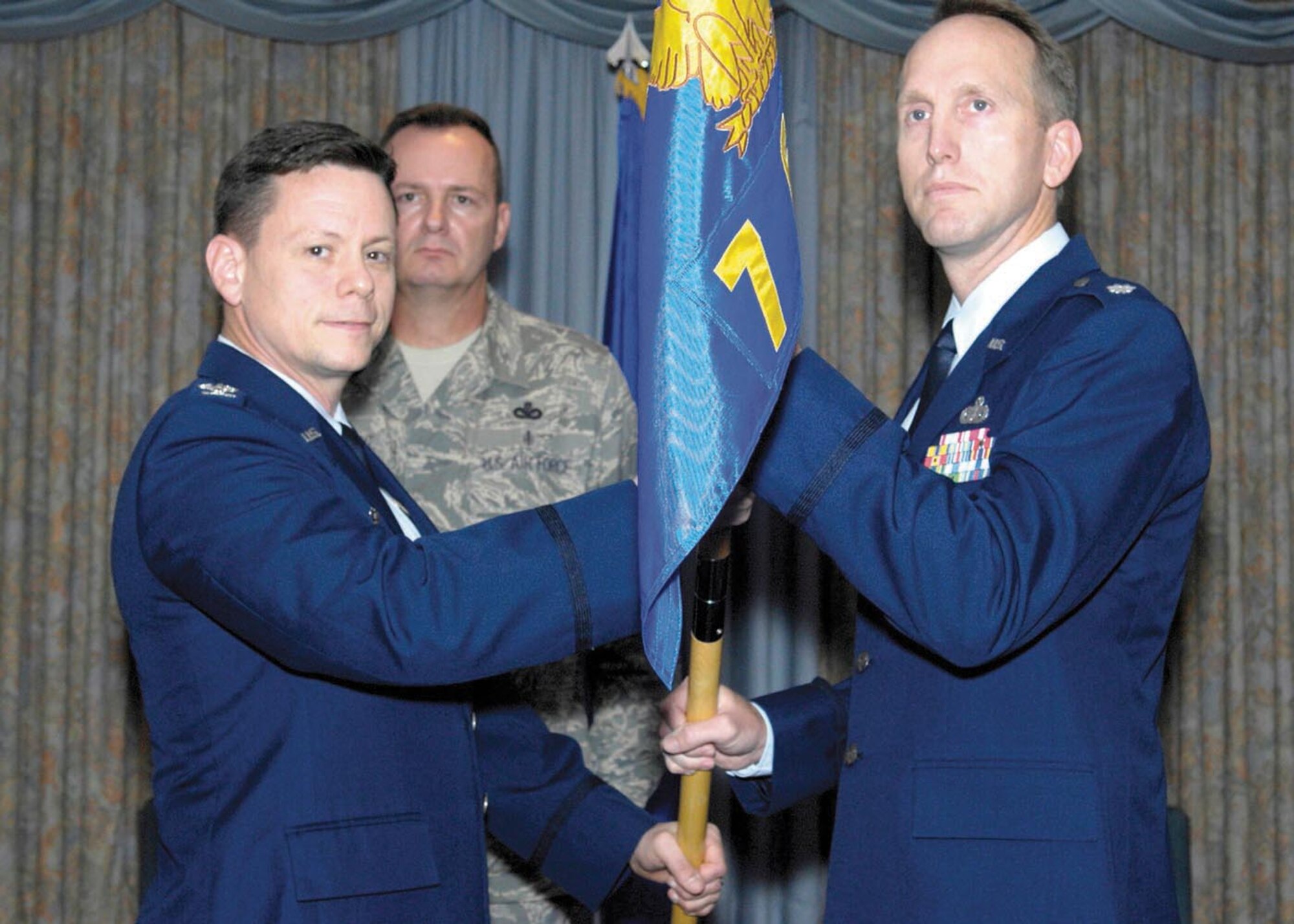 Colonel Wilkins F. Urquhart, commander, 3th Field Investigations Squadron, hands over the squadron guidon to Lt. Col. Adam C. Engleman, the new commander of the 7th Field Investigations Squadron during an assumption of command ceremony on Jul 28. Lt. Col. Engleman hails from Shaw AFB, S.C., where he was the director of the AFOSI Special Staff. (U.S. Air Force photo/Bobby Jones)