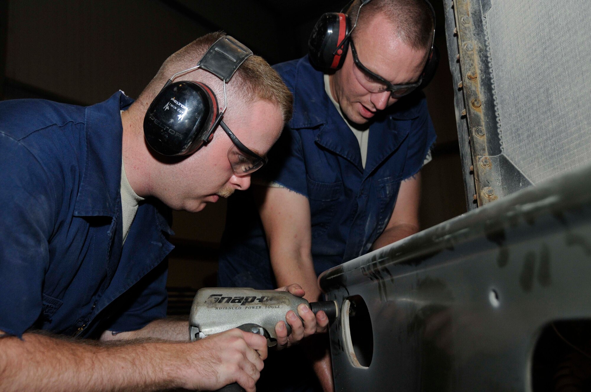 Senior Airman Kevin Downey, vehicle maintenance journeyman with the 1st Expeditionary Rapid Engineer Deployable Heavy Operational Repair Squadron Engineers (RED HORSE) Group, uses an air ratchet to secure a bumper bolt to a tractor while Staff Sgt. Nathan Sanders, special purpose vehicle maintenance journeyman with the 1st Expeditionary RED HORSE Group, holds the nut in place Aug. 11, 2008, at an undisclosed air base in Southwest Asia. Airman Downey and Sergeant Sanders are salvaging parts from an unserviceable truck and transferring to a useable truck in order to send it out to the field. The 1st Expeditionary RED HORSE Group performs heavy repair and construction projects throughout the US Central Command’s area of responsibility. Airman Downey, a native of Fulton, Mo., and Sergeant Sanders, a native of Ringgold, Ga., are both deployed from Misawa Air Base, Japan, in support of Operations Iraqi Freedom, Enduring Freedom and Joint Task Force-Horn of Africa. (U.S. Air Force photo by Staff Sgt. Darnell T. Cannady/Released)