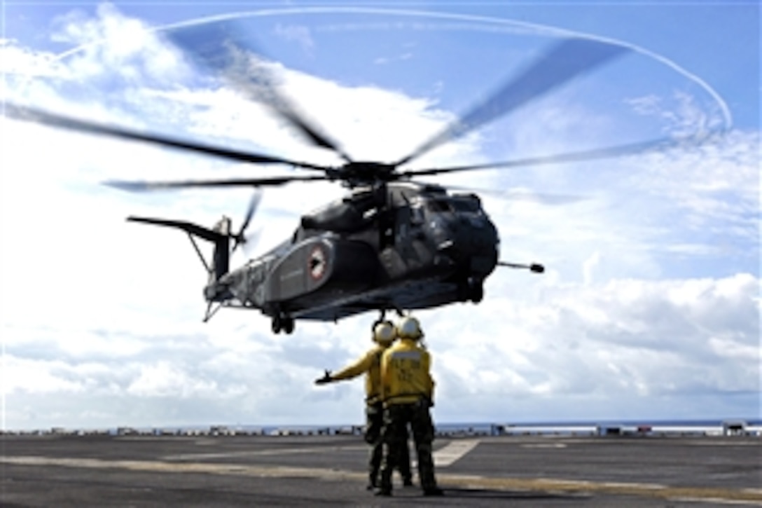 U.S. Navy Petty Officer 3rd Class Jonathan Lambes, left, and Melchor Navora direct a Sea Dragon helicopter for a landing on the flight deck of the amphibious assault ship USS Tarawa in the Pacific Ocean, Aug 8, 2008. 