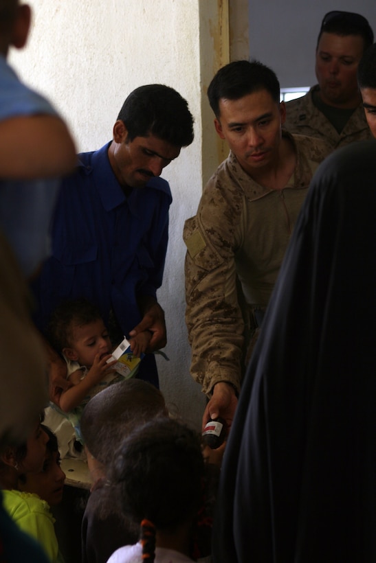 Navy Lt. Liu, battalion surgeon, 2nd Battalion, 3rd Marine Regiment, Regimental Combat Team 1, passes out prescribed medicine to Iraqis in Subyhat, Iraq during a cooperative medical engagement Aug. 12. The Island Warriors helped approximately 1,000 Iraqis by giving them medical treatment during the two-day event.