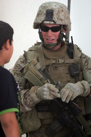 Cpl. Darnell G. Liesinger, 24, from Sioux Falls, S.D., who is a civil affairs team member with Civil Affairs team 5, 2nd Battalion, 11th Marine Regiment, Regimental Combat Team 5, shows an Iraqi boy his multi-tool during a meeting at the Rawah, Iraq, mayorâ??s office Aug. 12.  Liesinger is an individual ready reservist who has returned to active duty to serve as a civil affairs Marine.  Liesinger did three previous deployments to Iraq as an infantry Marine and is now transitioning from kicking in doors to shaking hands.::r::::n::