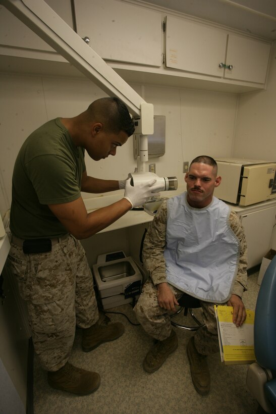 Navy Seaman Mark Arceneaux, , hospital corpsman, prepares Sgt. Dennis Bailey, chief cook, A Watch, Camp Wilson Mess Hall, for an x-ray Aug. 13 while on board the 23rd Dental Company’s Mobile Dental Unit at Camp Wilson. The MDU is designed to bring healthcare support to the active duty unit that has limited access to the main branch dental clinic.