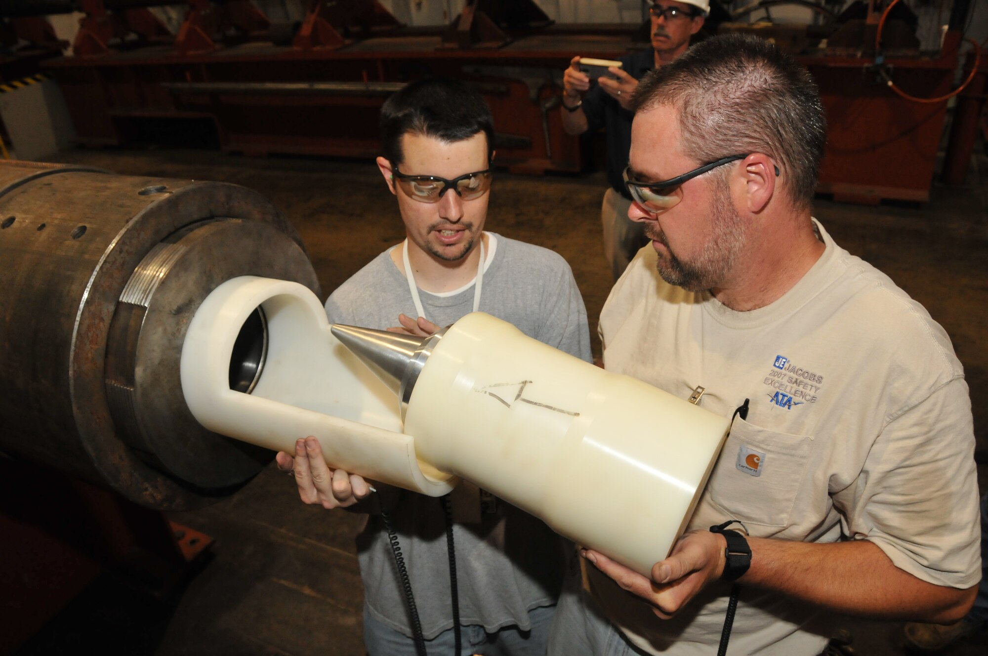 David Brown and Troy Perry, ATA outside machinists, install a slug projectile with a pitch motor installed into the 8-inch bore diameter barrel of AEDC’s Hypervelocity Range G’s launcher. This projectile will be launched out of the G Range two-stage light gas gun at a velocity of 8,200 feet per second.  This is the first test of a new rocket motor that will be used to pitch the Terminal High Altitude Area Defense (THAAD) projectile up to a predetermined angle prior to impacting simulated threat targets. The primary objective of this shot is to verify pitch motor ignition and performance. (Photo by David Housch)
