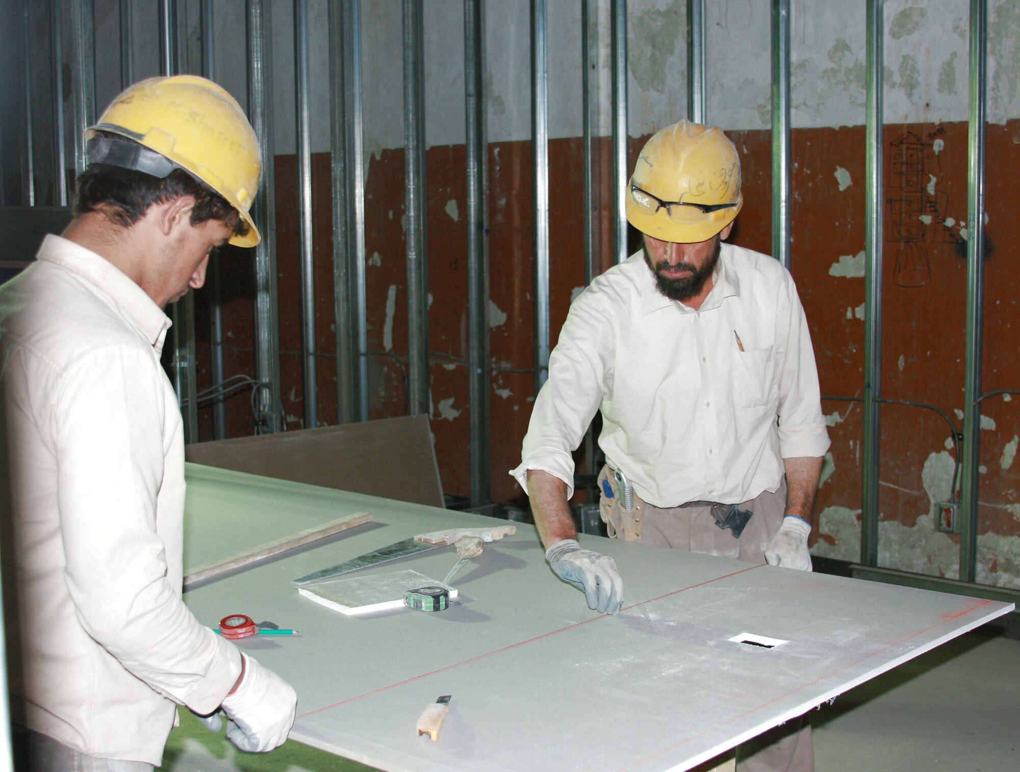 Two Afghan workers cut drywall for rooms inside a new $2.7 million Combined Joint Task Force-101 administrative building at Bagram Airfield, Afghanistan. Bagram's facility engineer team employs approximately 1,000 Afghan nationals at any given time. (Courtesy photo) 
