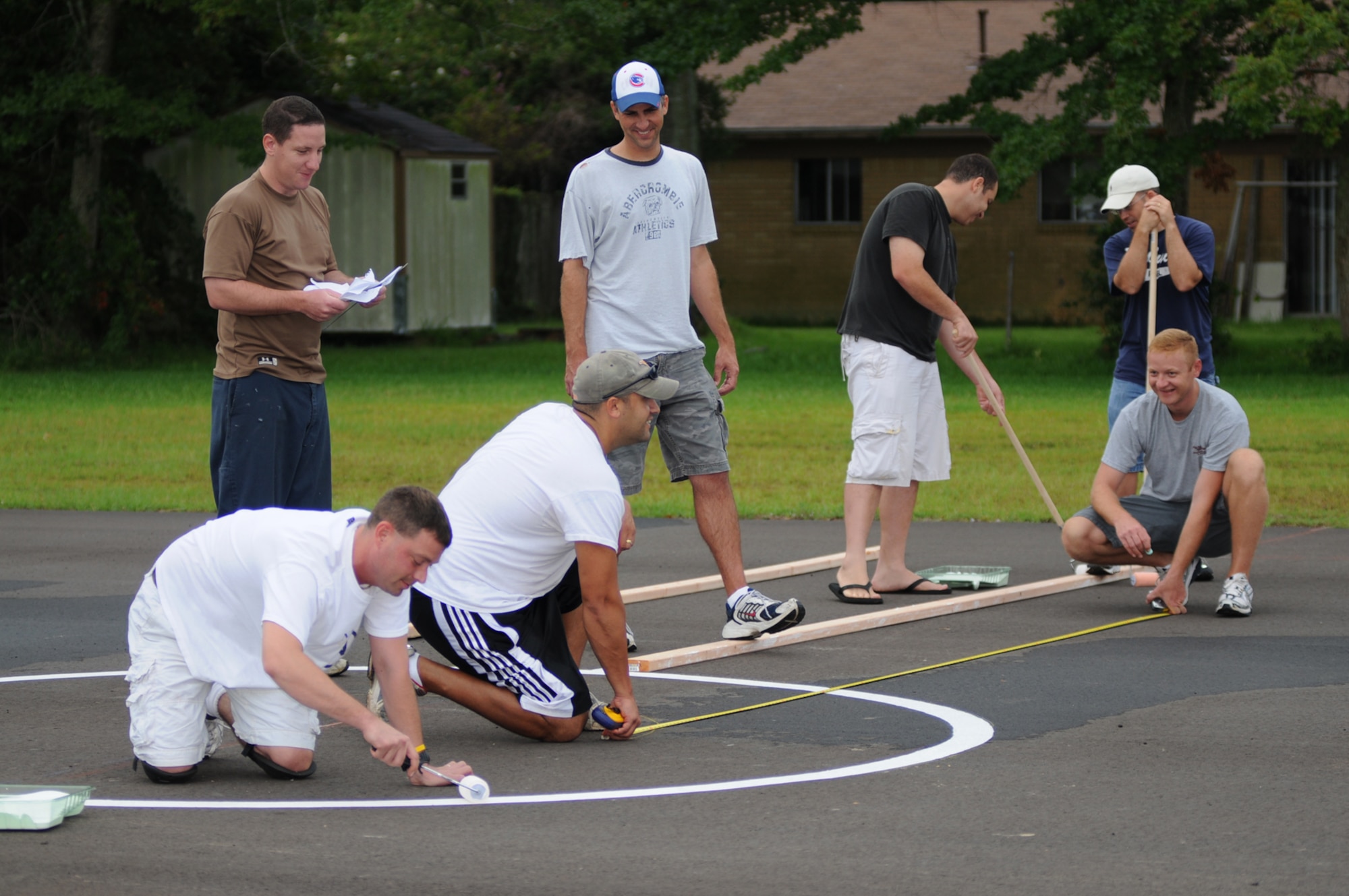 Foreground from left, Tech. Sgt. James Malone and Master Sgt. Chad Heilman, and back row from left, Capt. Michael Zink,Tech. Sgt. Jesse Goodwin, Petty Officer 1st Class Youssef Saab, Master Sgt. Michael Babbitt and Tech. Sgt. Joel Desjardins design, measure and paint the “combo court” at Pecan Park Elementary School in Ocean Springs.  All are instructors in the 332nd Training Squadron.  Petty Officer Saab is assigned to the Center for Naval Aviation Technical Training Unit.  (U.S. Air Force photo by Kemberly Groue)