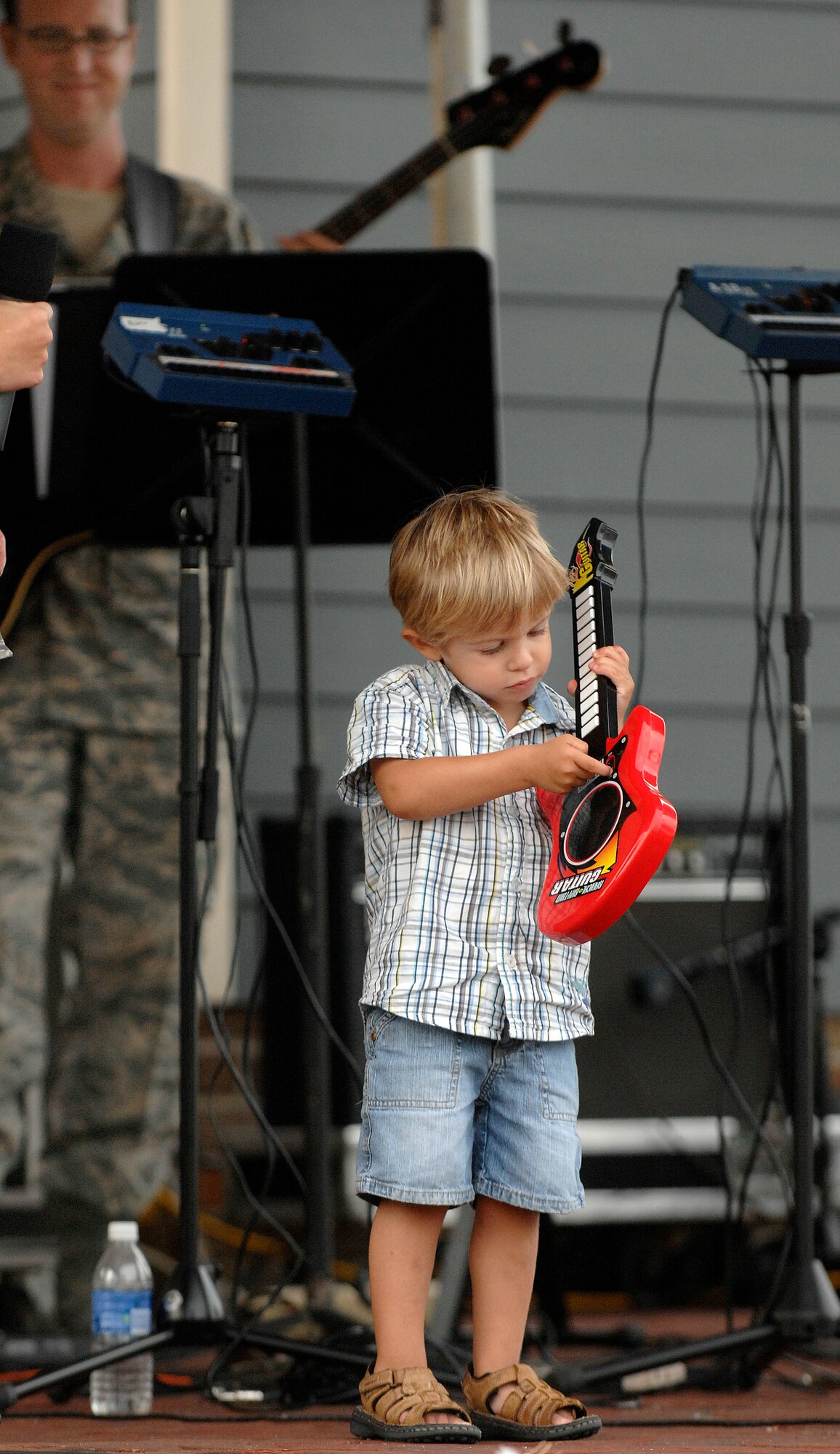 LANGLEY AIR FORCE BASE, Va. -- Micah Beers, son of Staff Sgt. Bryan Beers, 1st Civil Engineer Squadron, attempts to play his guitar during the Air Combat Command Heritage of America Band concert in Yorktown, Va. Aug. 12.  Micah was randomly selected from the crowd to play with the band during the concert to entertain the local community.  The ACC Heritage of America Band perform during the summer months to connect with the local community.   (U.S. Air Force photo/Senior Airman Vernon Young)