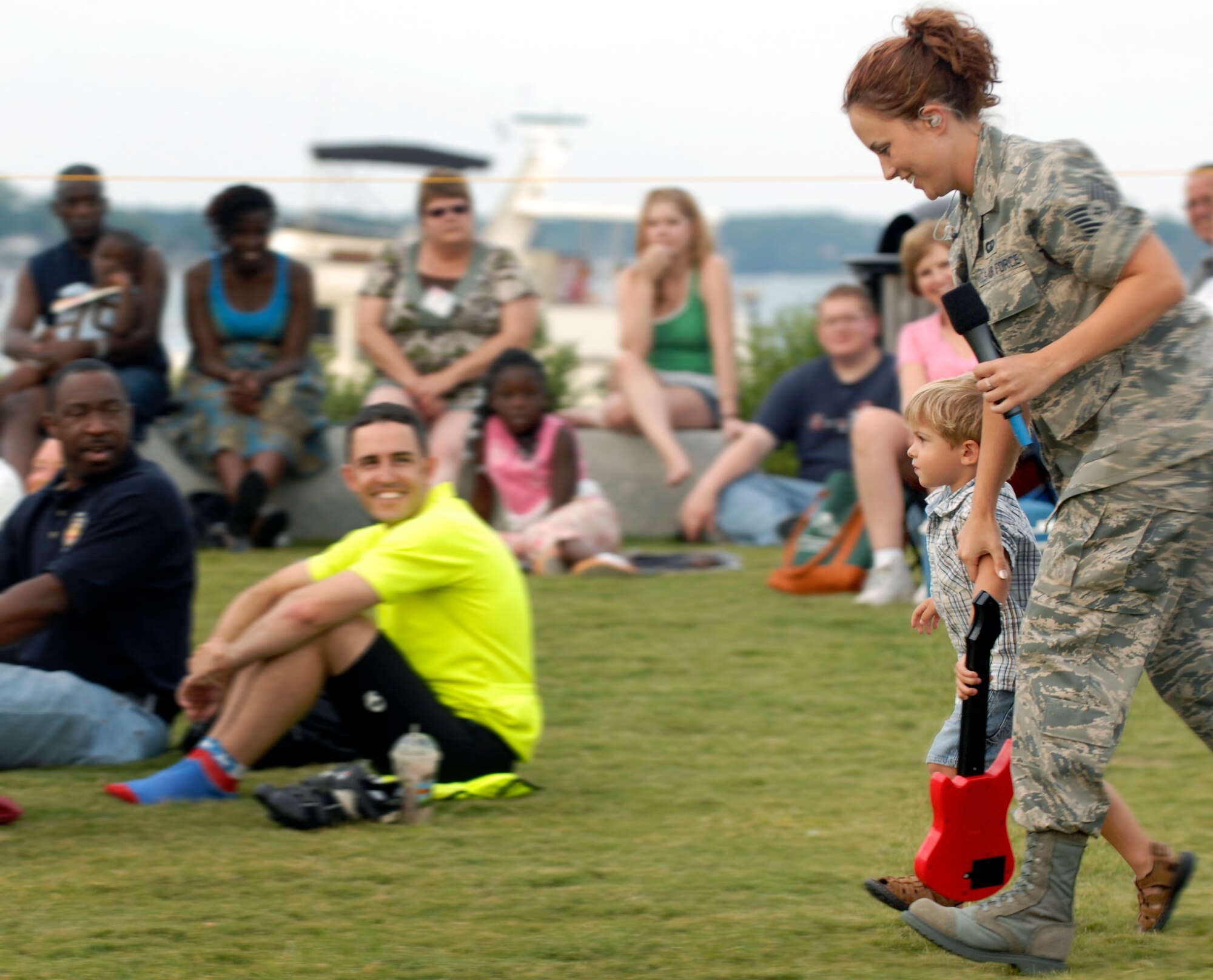 LANGLEY AIR FORCE BASE, Va. -- Tech. Sgt. Beck Wolf, Air Combat Command Heritage of America Band vocalist, runs with Micah Beers, son of Staff Sgt. Bryan Beers, 1st Civil Engineer Squadron, during a concert in Yorktown, Va. on Aug. 12.  Sergeant Wolf surprised the crowd by selecting one of the youngest attendees to help the band.  The ACC Heritage of America Band performs during the summer months to connect with the local community and is scheduled to perform again on Aug. 19.  (U.S. Air Force photo/Senior Airman Vernon Young)