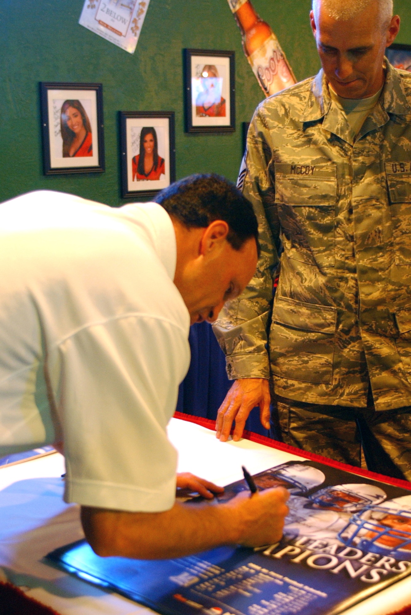 Chief Master Sgt. Kevin McCoy gets a U.S. Air Force Academy football poster signed by Falcon’s Coach Troy Calhoun Aug. 12 at the Peterson Air Force Base Club in Colorado. “I talked to him about the season and we talked about my son and taking him to Falcon games,” Chief McCoy, 21st Medical Group said. “Definitely thinking about taking my son to the Navy versus Air Force game. I think he’d have a blast seeing the camaraderie of the cadets from both services going back and forth.” Coach Calhoun was at the Club’s Stripes Pub for a lunch-time talk about the upcoming USAFA football season. There, he took questions from the audience and signed autographs. (U.S. Air Force photo/Margie Arnold) 