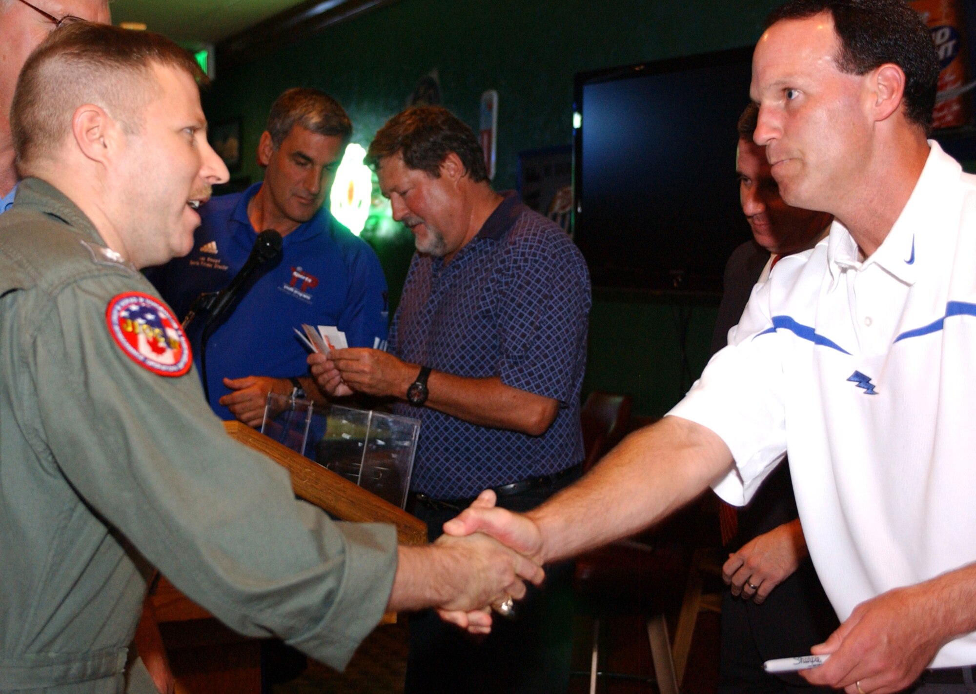 Navy Cmdr. Lloyd Cafran shakes hands with U.S. Air Force Academy Football Coach Troy Calhoun Aug. 12 at the Peterson Air Force Base Club in Colorado. Coach Calhoun was at the Club’s Stripes Pub for a lunch-time talk about the upcoming USAFA football season. There, he took questions from the audience and signed autographs. Commander Cafran is assigned to the North American Aerospace Defense Command/U.S. Northern Command. (U.S. Air Force photo/Margie Arnold)