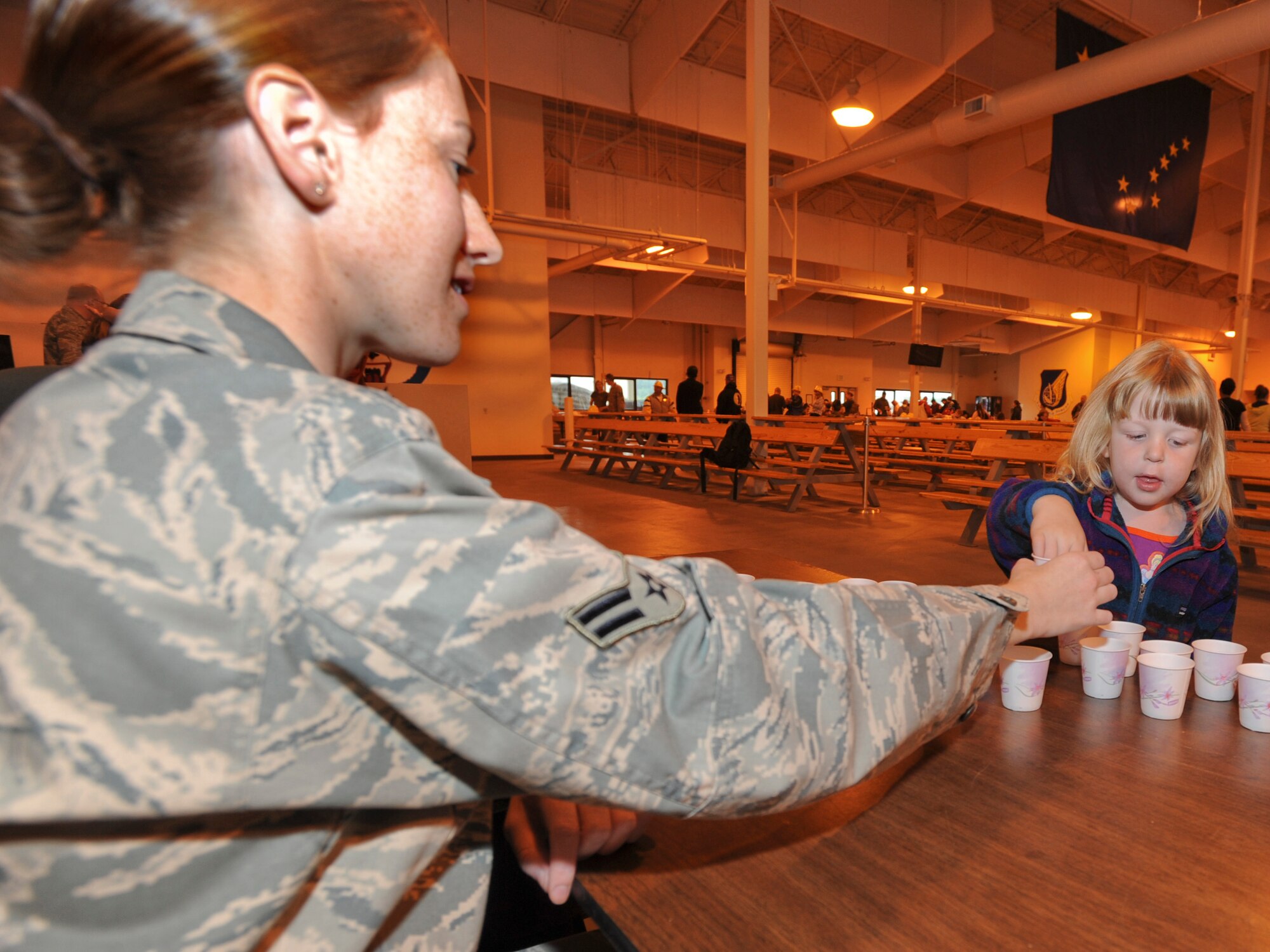 ELMENDORF AIR FORCE BASE, Alaska -- Daphne Fish takes her medicine tablets from Airman 1st Class Erica Scott, 3rd Aerospace Medicine Squadron, at the public health booth during Operation Family Topcover. The medicine handed to family members signifies the immunizations that military members might encounter prior to deploying. Operation Family Topcover allowed family members the oppurtunity to witness first hand what their military members encounter prior and during their deployments. (U.S. Air Force photo/Staff Sgt. Joshua Garcia)