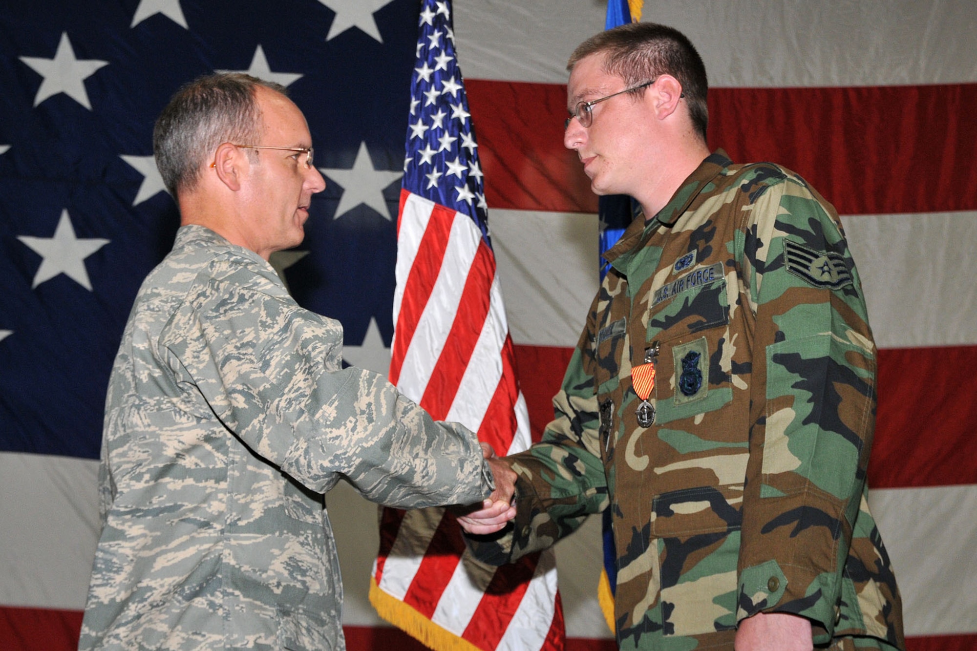 Col. Michael Fortney, 341st Missile Wing commander, congratulates Staff Sgt. Michael Rodden, 741st Missile Security Forces Squadron, after presenting him with the Air Force Combat Action Medal during a commander's call Aug. 6. (U.S. Air Force photo/John Turner)