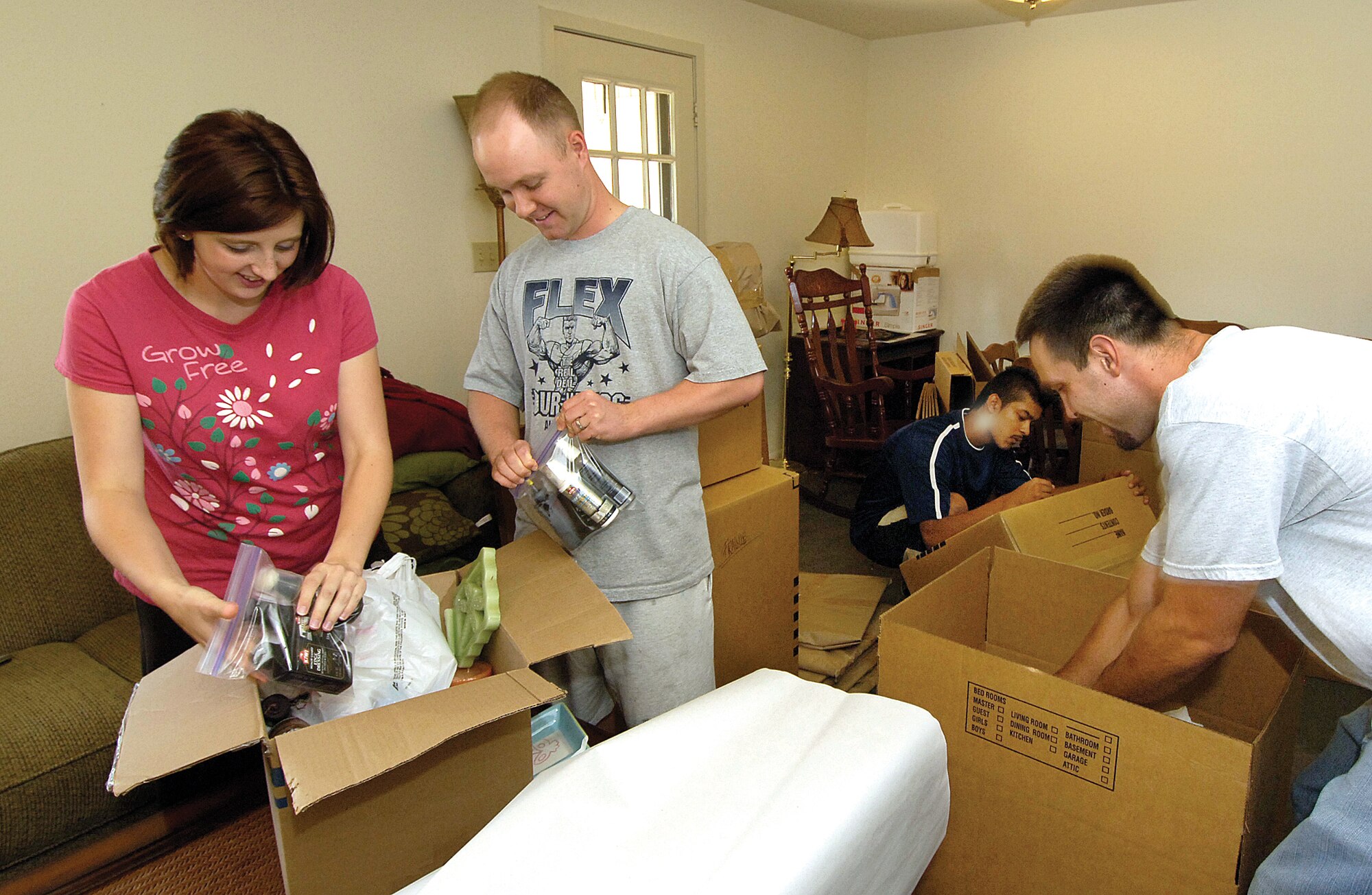 Staff Sgt. Tyler Sosh and his wife, Allison, pack personal items as they prepare to move from Tinker to Charleston Air Force Base, S.C.  Aztec Moving Company personnel Hugo Chavez, back, and Jordan Ferrer, right, pack the couple’s home for their first permanent change of station move since the 34th Combat Communications Squadron Airman left technical school.(Air Force photo/Margo Wright)