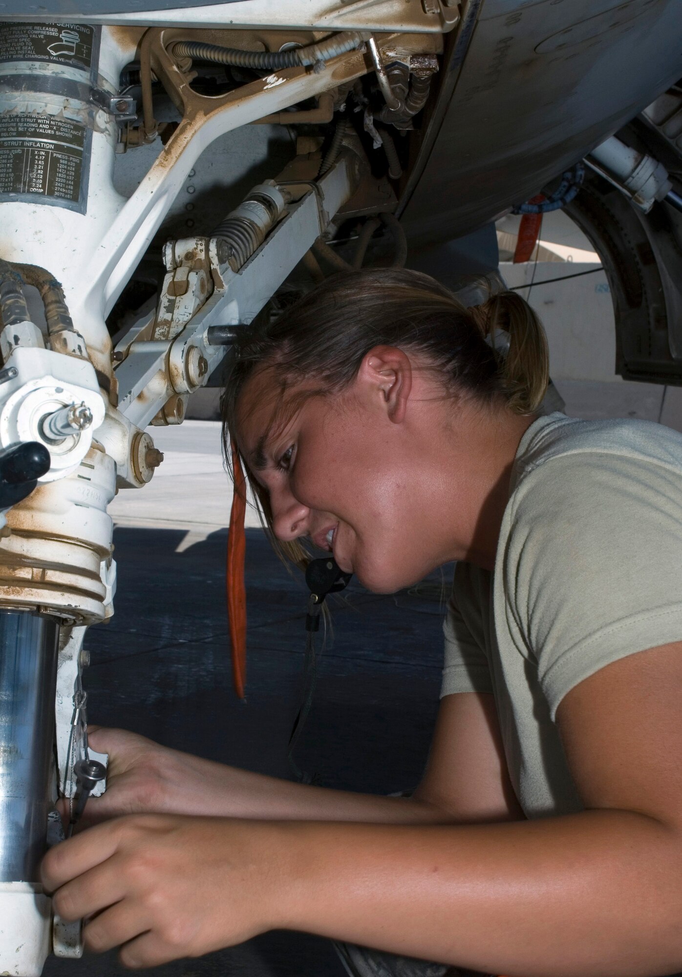 JOINT BASE BALAD, Iraq -- Senior Airman Kimberly Bickford reconnects T-links on the center landing gear of an F-16 Fighting Falcon here Aug. 12. Removal of the T-links on the landing gear allows the fighter to be towed with a tractor and tow bar. Airman Bickford is deployed from Hill Air Force Base, Utah. (U.S. Air Force photo/Tech. Sgt. Erik Gudmundson)