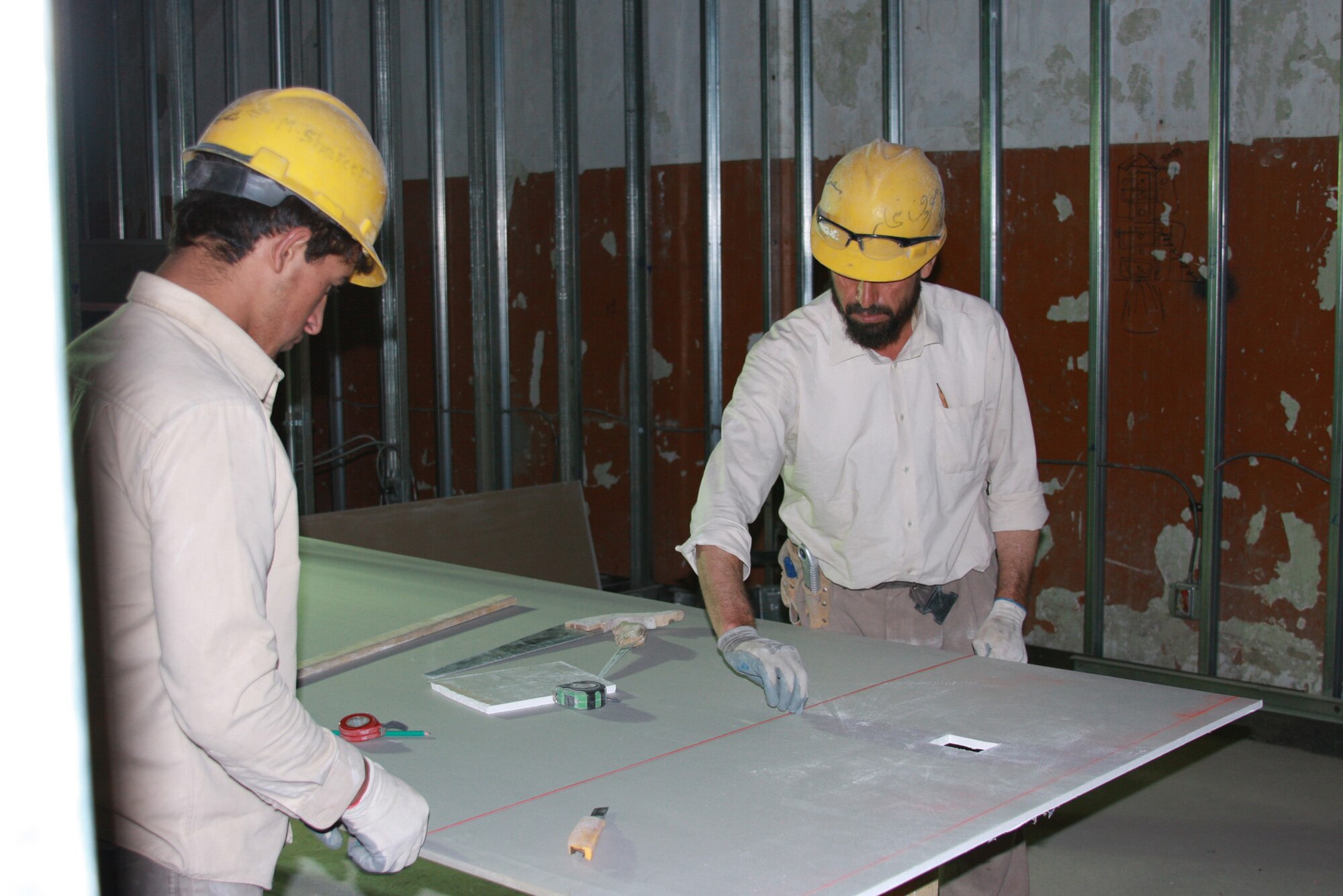 Two Afghan workers prepare to cut drywall for rooms inside a new $2.7 million Combined Joint Task Force-101 administrative building on Bagram Air Field, Afghanistan. Bagram’s Facility Engineer Team employs approximately 1,000 Afghan nationals at any given time. (Courtesy photo)