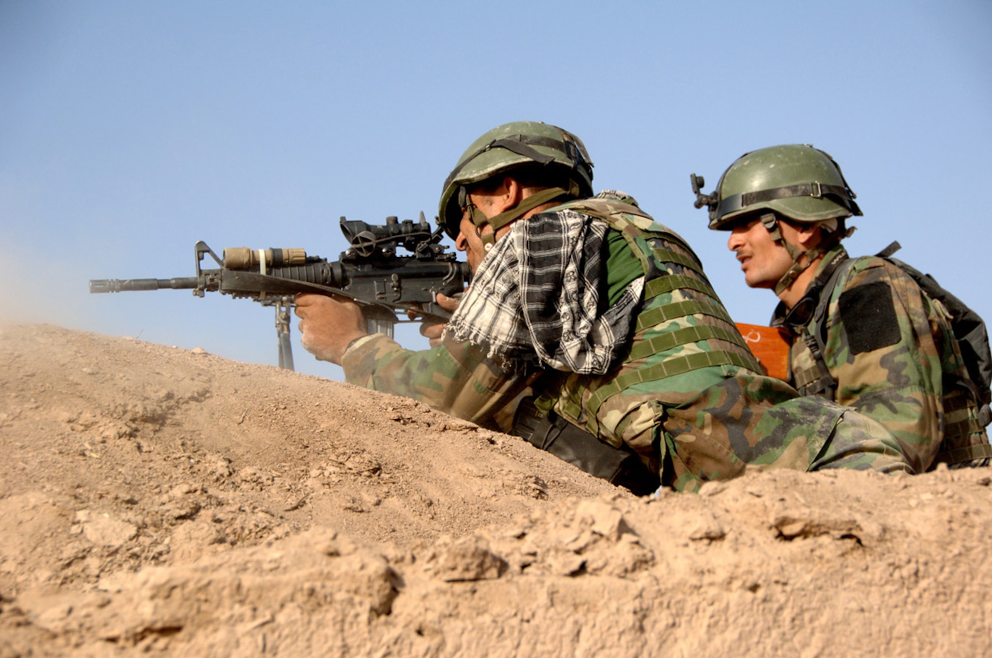An Afghan National Army Commando fires upon enemy insurgents using an M-4 carbine rifle in the Zerkoh Valley near Parmakan, Afghanistan, Herat province.  (U.S. Army photo/Spc. Curtis Loter)