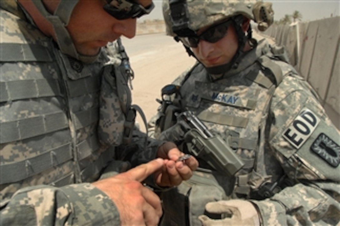 U.S. Air Force Tech. Sgt. Jeremiah Grisham (left) and Staff Sgt. Christian McKay examine shrapnel outside a joint security station in Eastern Baghdad, Iraq, on Aug. 10, 2008.  Grisham and McKay are both explosive ordnance disposalmen attached to the 4th Brigade Combat Team, 10th Mountain Division.  