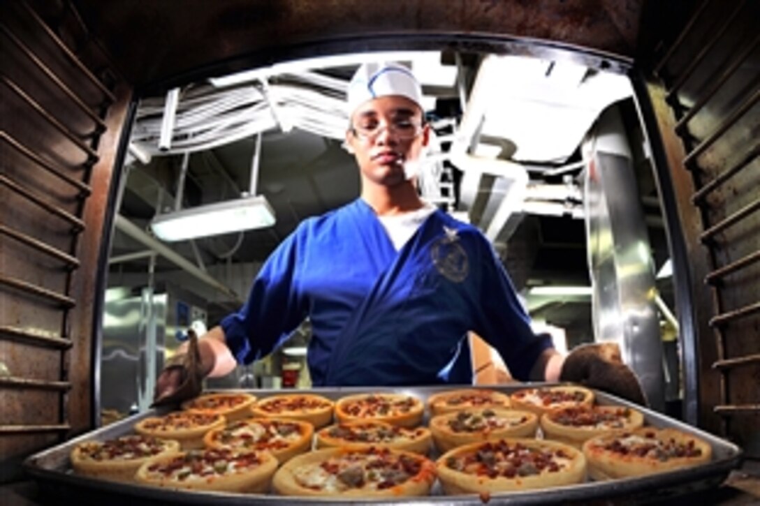 U.S. Navy Petty Officer 3rd Class Gabriel Common, a culinary specialist, takes pizzas out of the oven in the aft galley aboard the aircraft carrier USS Abraham Lincoln in the North Arabian Sea, Aug. 9, 2008. 
