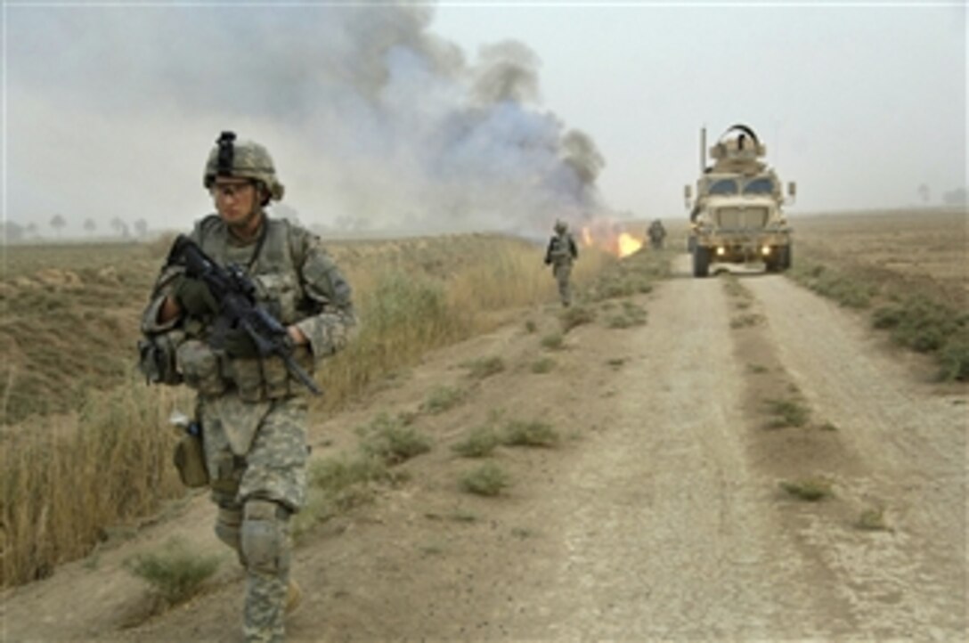 U.S. Army Sgt. Daniel Kear makes his way down a road after canal vegetation is set ablaze in Tahwilla, Iraq, on July 30, 2008.  Extremists use the concealment provided by the canal system to place IED's under the cover of night.  Kear is with Bravo Company, 1st Battalion, 6th Infantry Regiment, assigned to Task Force 1-35 Armor, 2nd Brigade Combat Team, 1st Armored Division.  