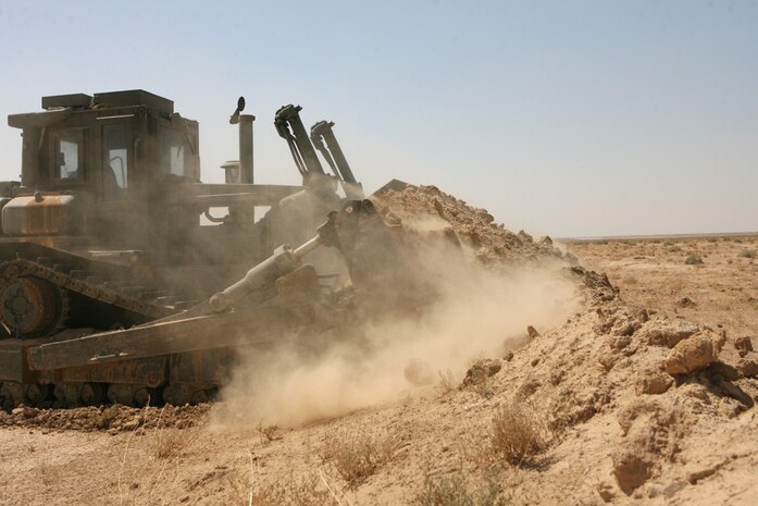 A bulldozer pushes up dirt Aug. 13 to create a berm along the Iraq and Syrian border in order to control people crossing the border illegally. Marines with Support Platoon, Company A, 3rd Combat Engineer Battalion, Regimental Combat Team 5 added approximately 30,000 yards of berm to the border, which now stretches along the entire Iraq and Syrian border. The purpose of the berm is to alleviate pressure on the Iraqi Security Forces and allow them to grow and become more established so they can better protect the people.