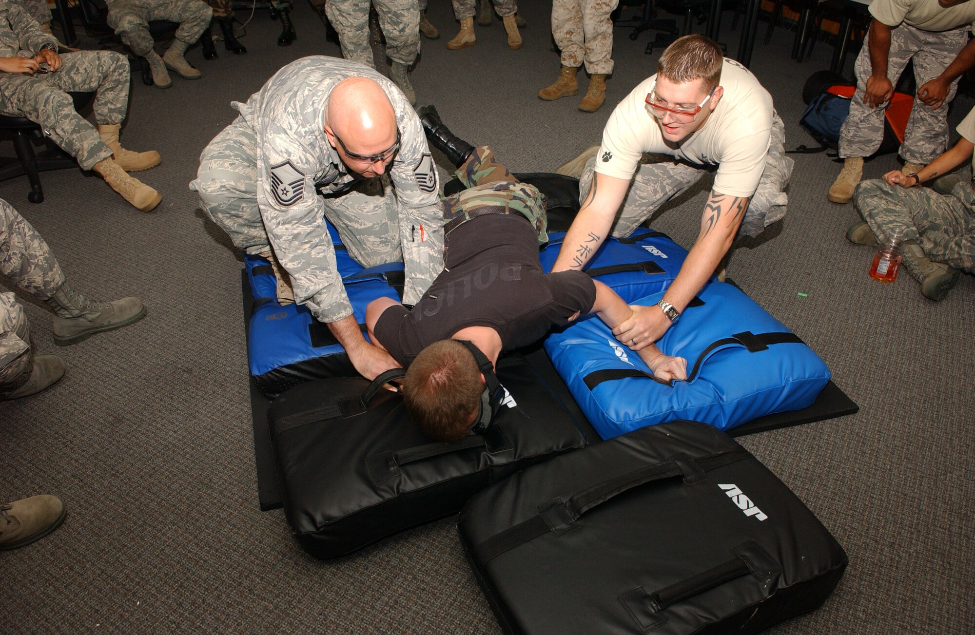 Airman 1st Class Bryan Hunt, 374th Security Forces Squadron patrolman, is being carried to the ground by Master Sgt David Day, 374th SFS alpha flight chief, and  Tech. Sgt. Christopher Manning, 374th SFS military working dog handler, while being shocked in the back by the X26C taser August 14 during training. Members of the 374th SFS participated in taser training and some volunteered for live demonstrations of the non-lethal weapon.                                
