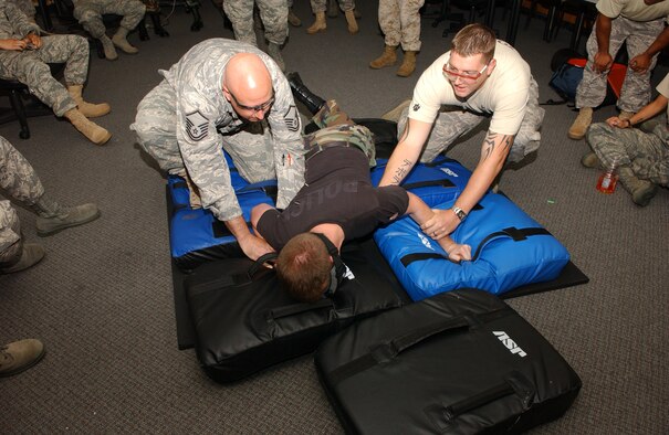 YOKOTA AIR BASE, Japan -- Airman 1st Class Bryan Hunt, 374th Security Forces Squadron patrolman, is carried to the ground by Master Sgt. David Day, 374th SFS alpha flight chief, and Tech. Sgt. Christopher Manning, 374th SFS military working dog handler, while being shocked in the back by the X26C taser during training Aug. 14. Members of the 374th SFS participated in taser training and some volunteered for live demonstrations of the non-lethal weapon.  (U.S. photo by Airman 1st Class Eric Summers)