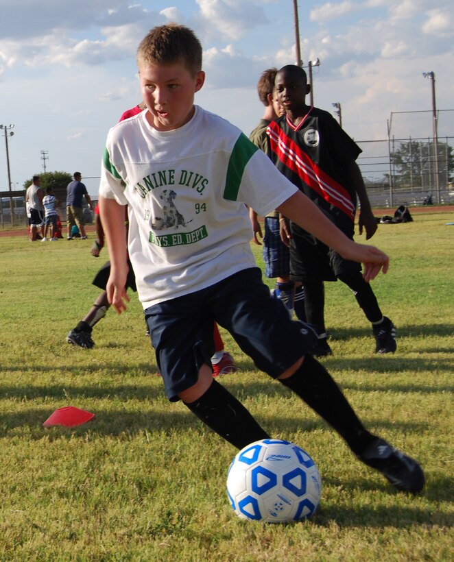 Whyatt Kiewicz, 9, practices passing the ball at the Madrigal Youth Center Soccer Clinic for Kids Aug.14. The clinic was held as a practice session to prepare for the fall soccer season. Members of the Midwestern State University Girls Soccer Team helped the children practice various soccer drills and techniques. (U.S. Air Force photo/Airman 1st Class Candy Miller) 