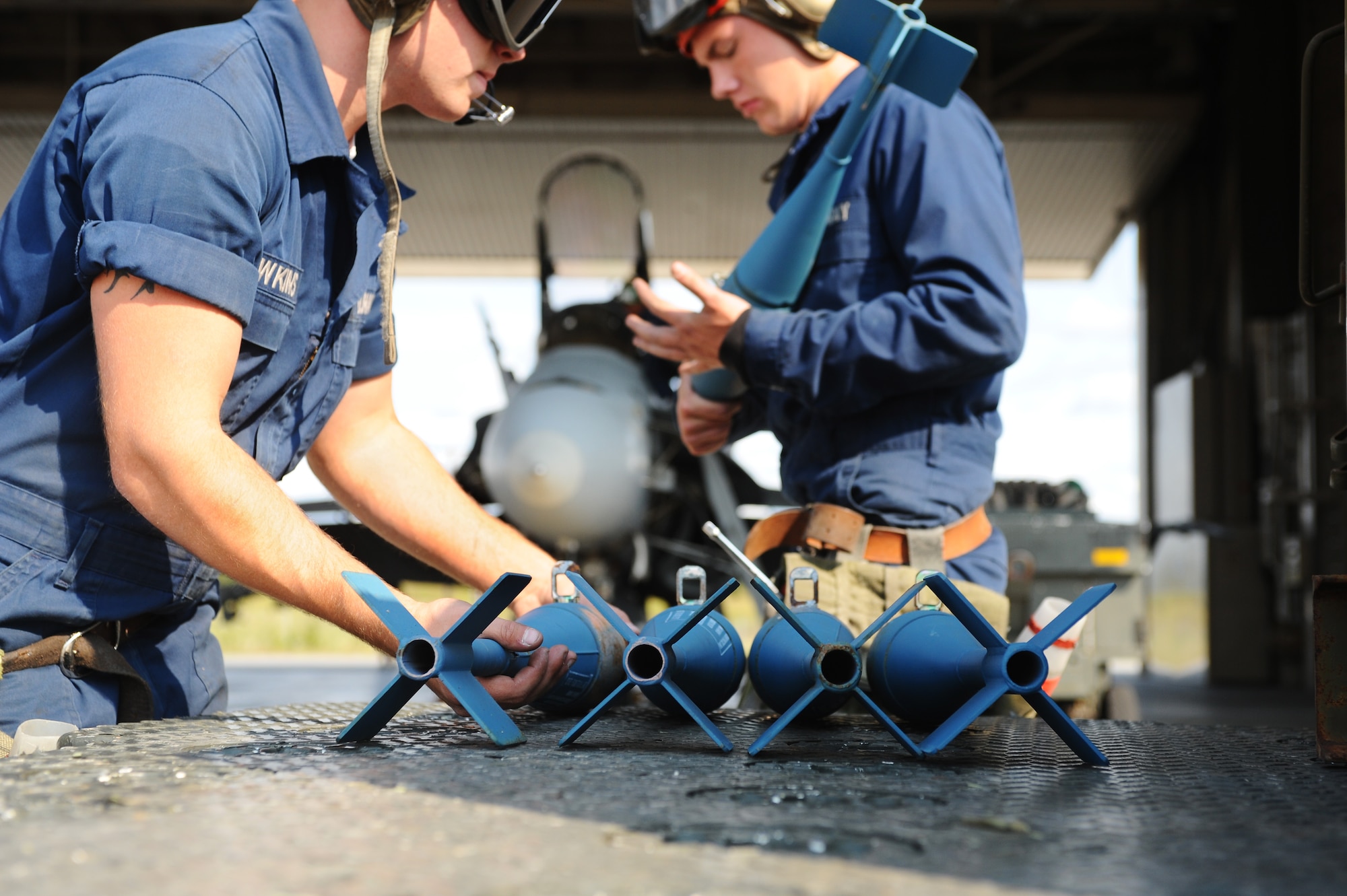 Airman Justin Hawkins, left, grabs an MK-76 practice bomb while Aviation Apprentice David Haitsch carries one over to a Navy F/A-18 Hornet Aug. 13, 2008, at Eielson Air Force Base, Alaska. Navy Strike Fighter Squadron 125, based out of Naval Air Station Lemoore, Calif., is currently conducting air-to-ground target training here by utilizing the 67,000 square mile Pacific Alaskan Range Complex. During this training new fighter pilots are gaining the qualification they need before they are sent to the fleet. Both are assigned to the VFA-125 Squadron Augment Unit.  (U.S. Air Force photo by Airman 1st Class Jonathan Snyder)