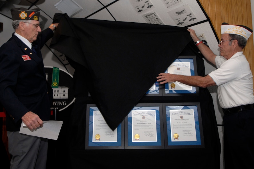 BARKSDALE AIR FORCE BASE, La. -- Kenneth Koval, Veterans of Foreign Wars member, and Phillip Volz, VFW district 12 commander, unveil six plaques dedicated to the crew members of Raider 21 during a presentation held at the Eighth Air Force Museum here Aug. 12. (U.S. Air Force photo by Airman 1st Class Joanna M. Kresge)